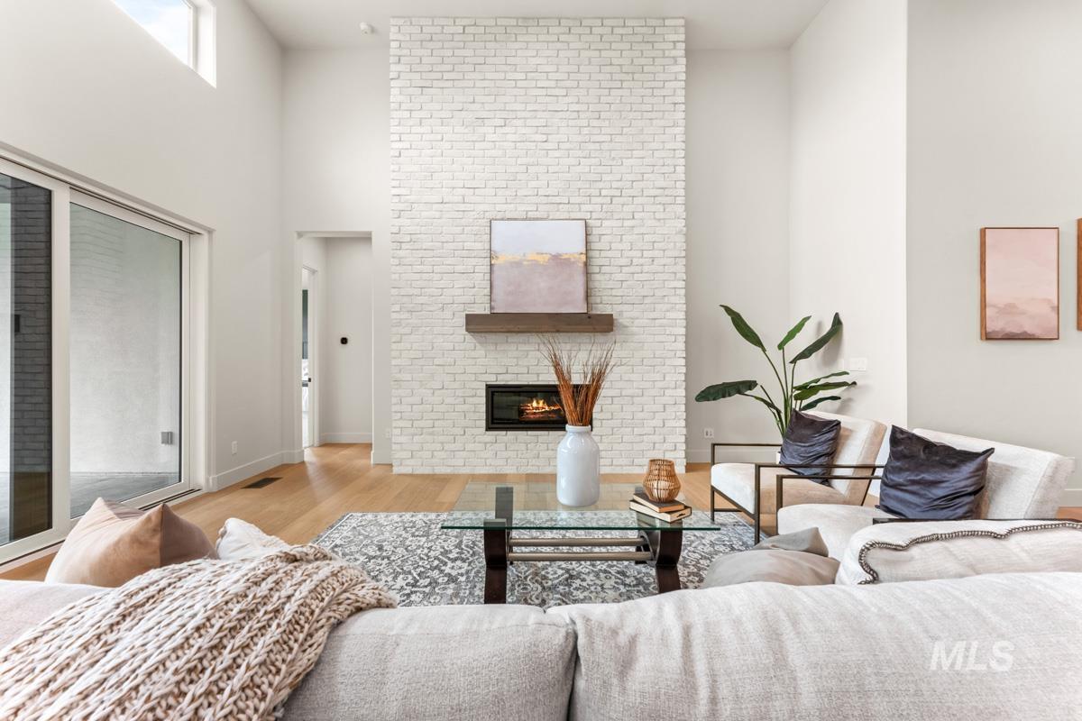 Vaulted ceilings highlight a floor-to-ceiling white brick fireplace with a wood mantel and built-in modern gas insert