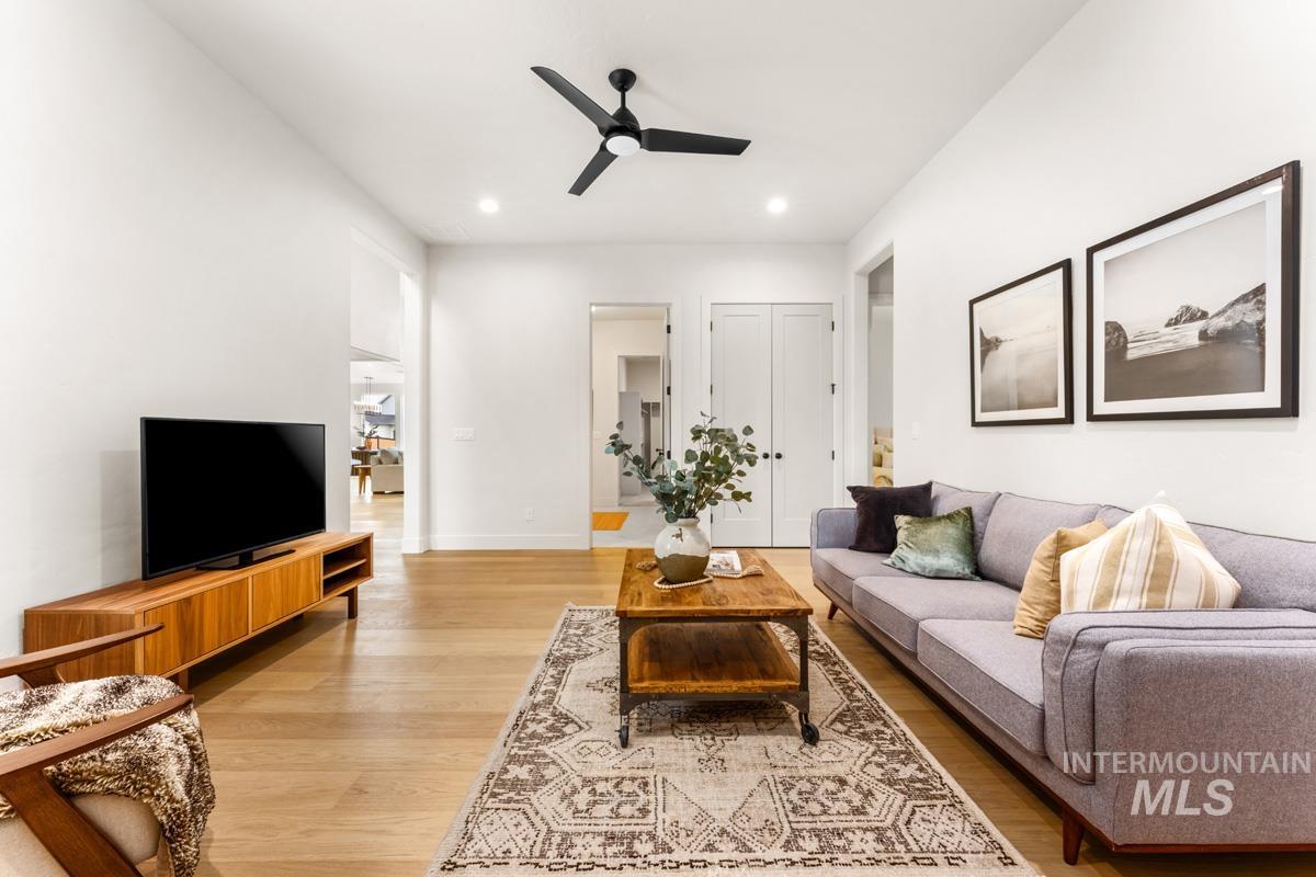 Spacious living area featuring light wood-finish flooring, recessed lighting, and a contemporary ceiling fan