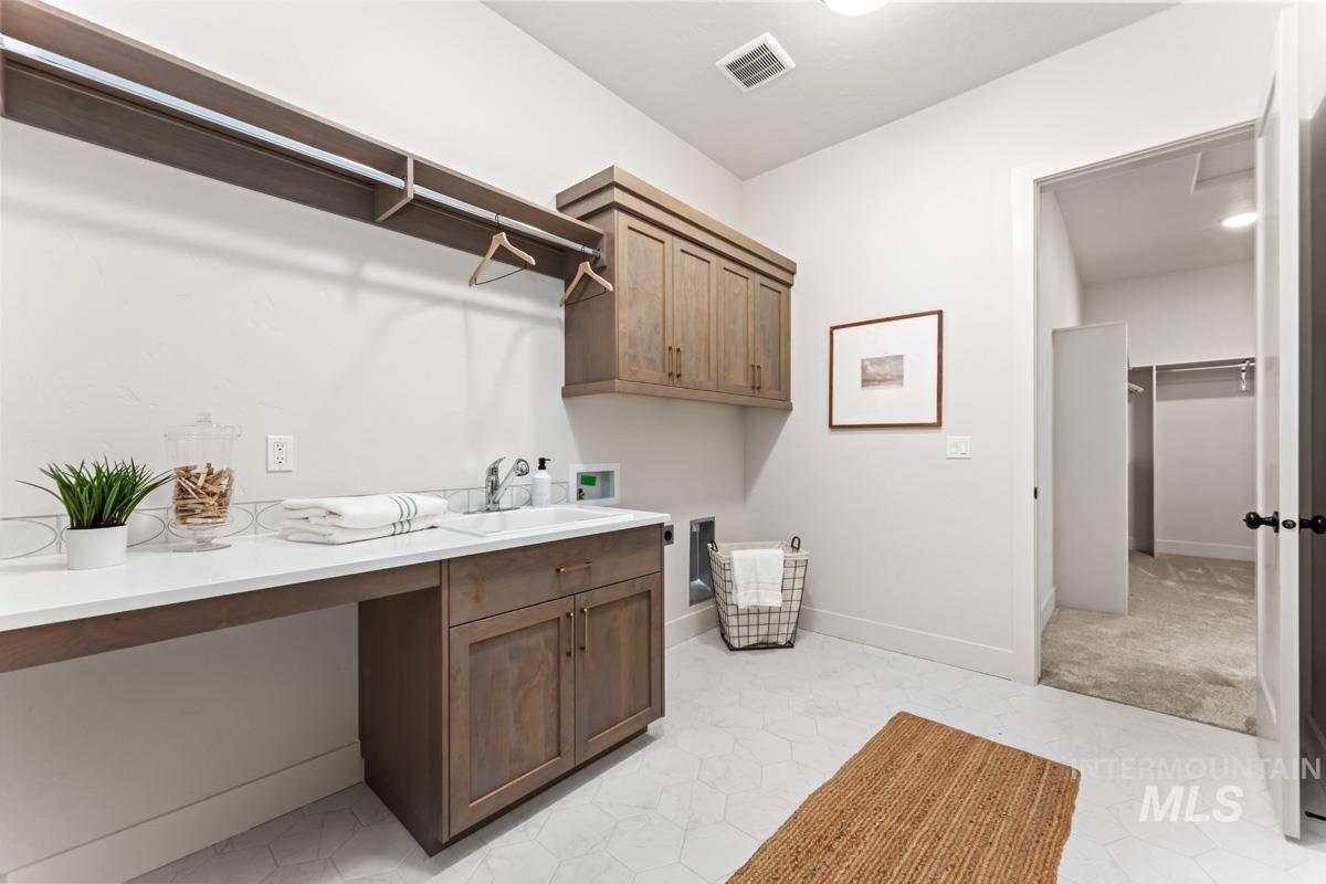 Utility room featuring a built-in sink with a countertop, wood-finish cabinetry, and hexagon tile flooring