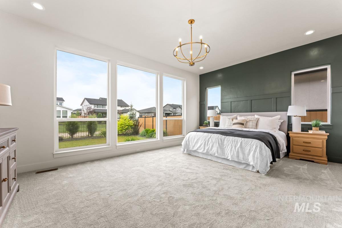 Expansive room featuring a paneled accent wall, large windows, recessed lighting, and a prominent gold-finish chandelier