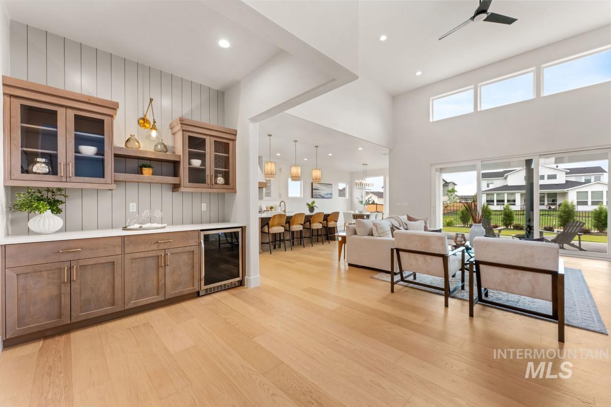 Contemporary living area featuring vaulted ceilings, ample natural light from upper and sliding glass windows, and light wood-finish flooring