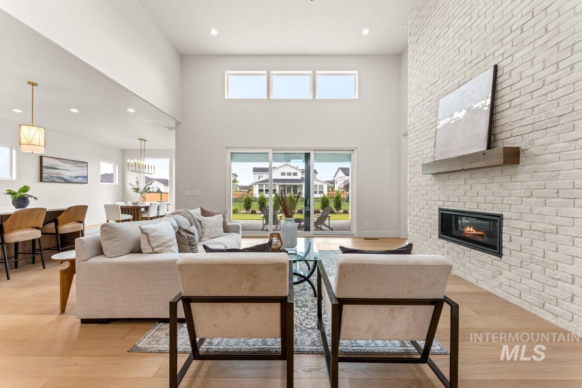 Spacious living area featuring a striking floor-to-ceiling white brick fireplace with a wood mantel