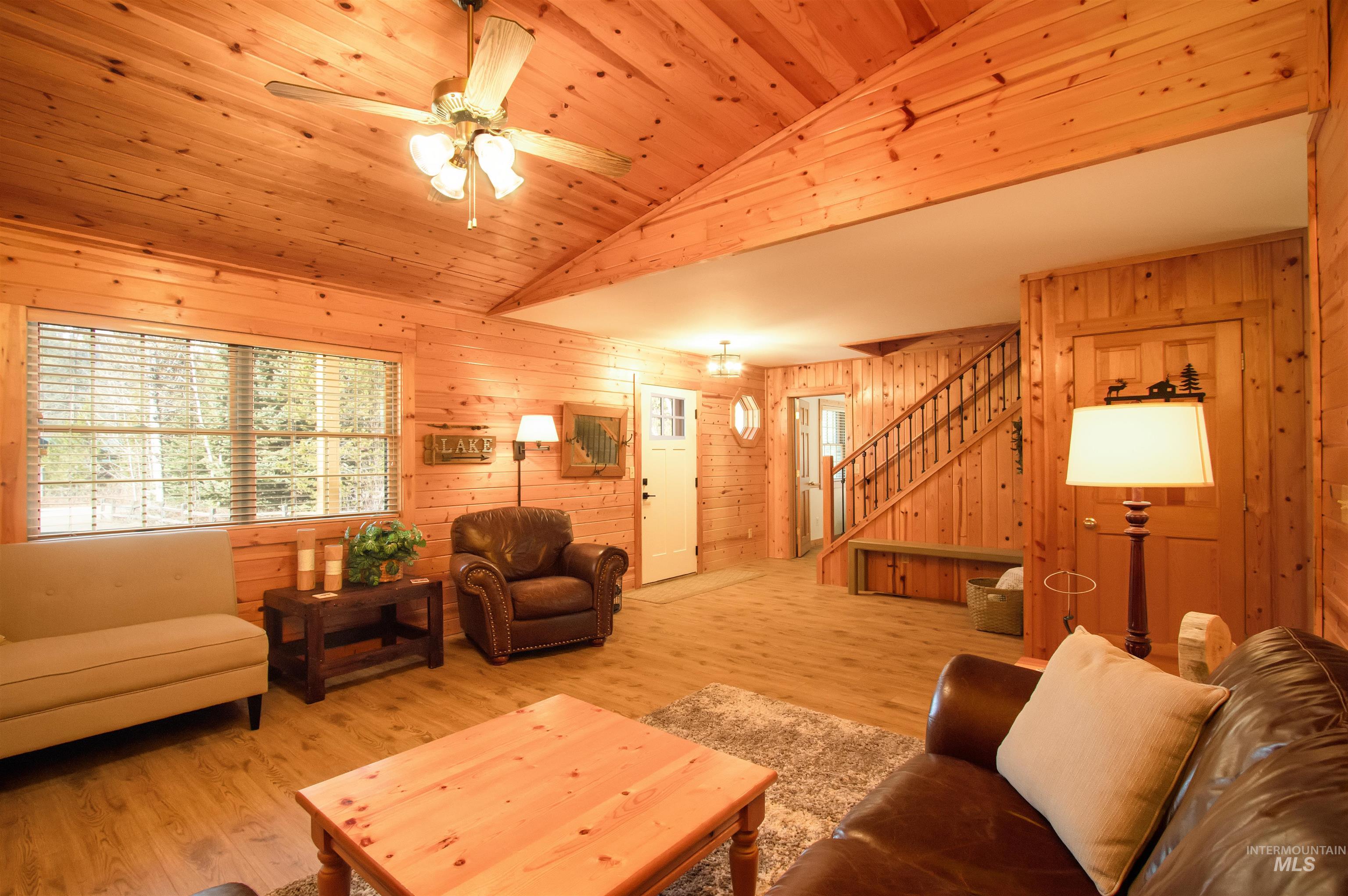 Living area featuring wood walls, a ceiling fan, wood finished floors, and a vaulted wood ceiling