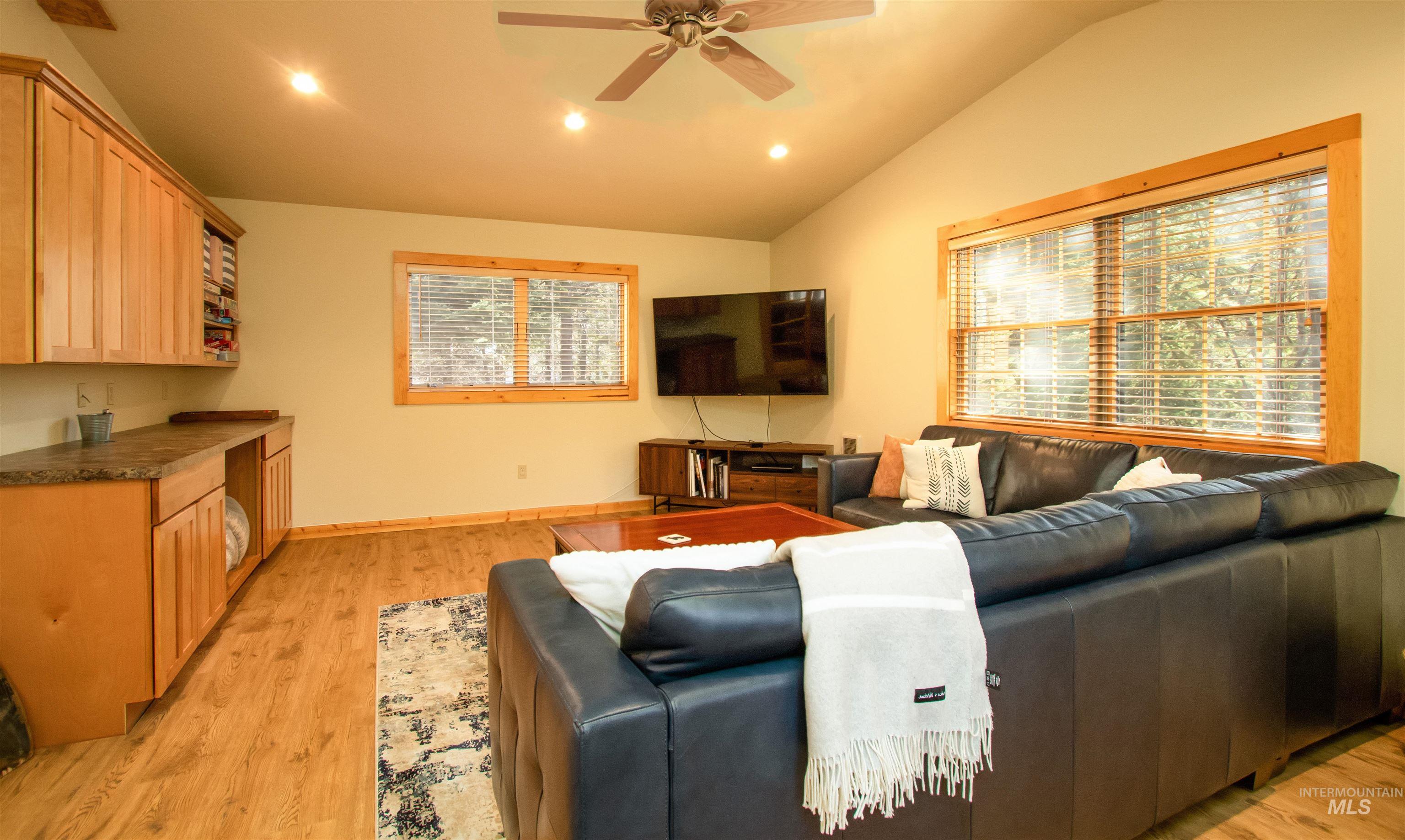 Living room with recessed lighting, lofted ceiling, ceiling fan, and light wood-style floors