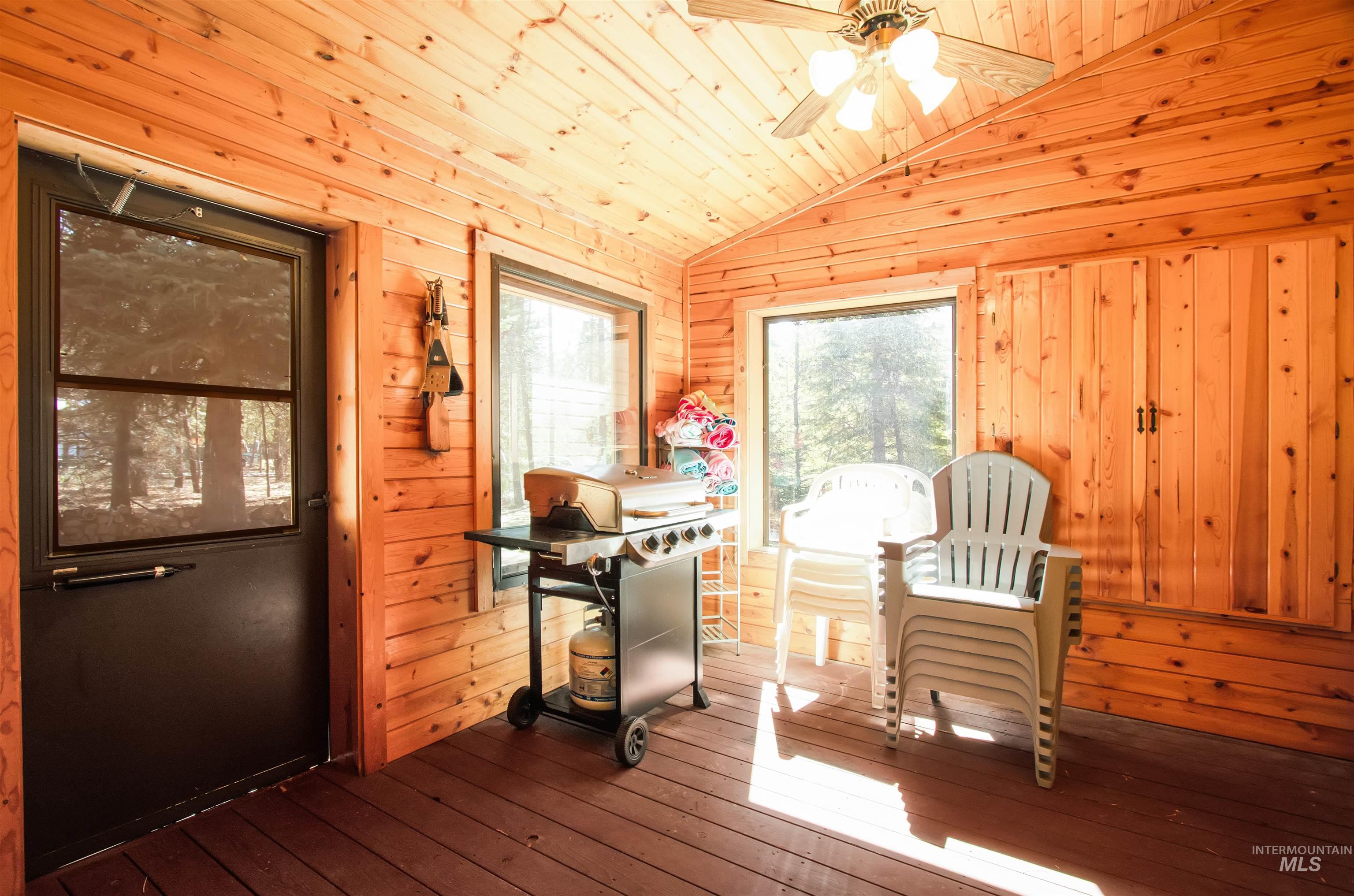 Dining room featuring a ceiling fan, hardwood / wood-style flooring, a vaulted wood ceiling, and wood walls