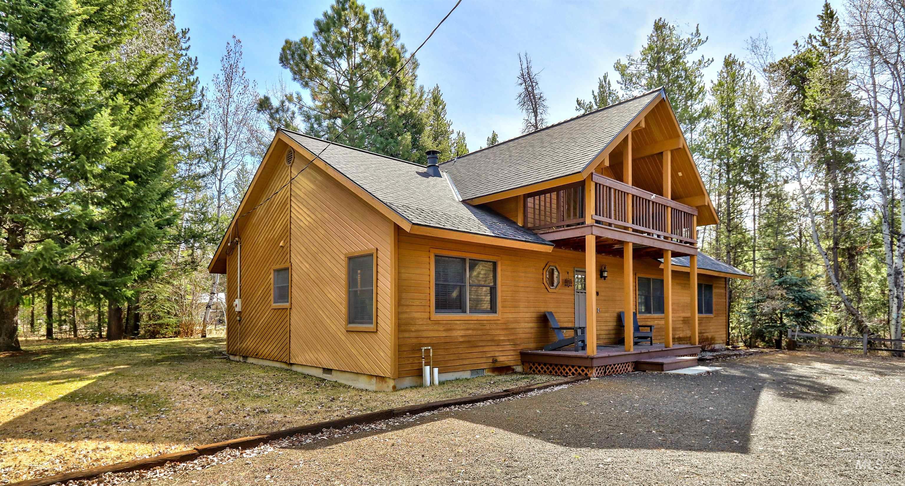 Rear view of house featuring a shingled roof, a yard, and a balcony