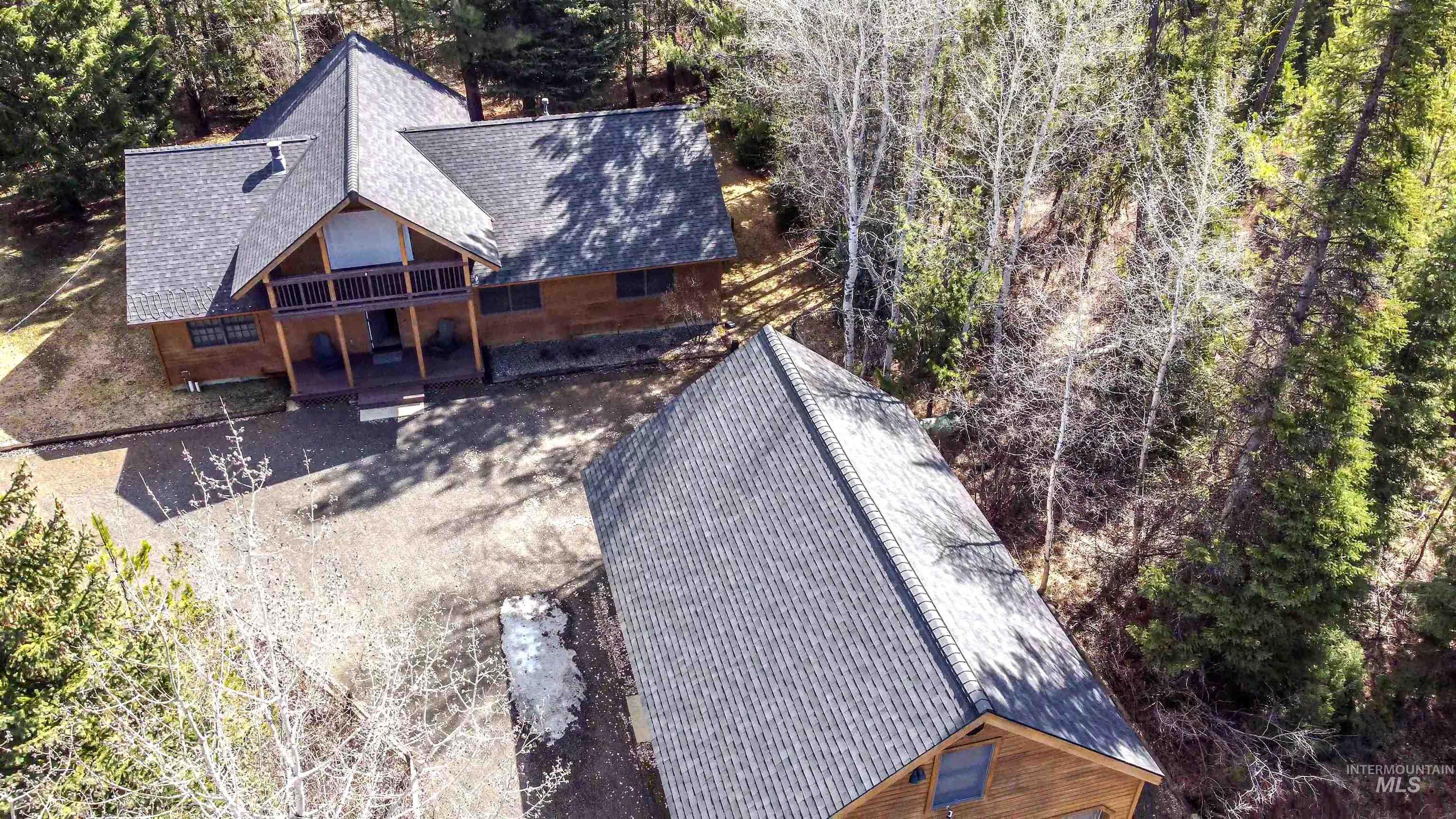 Aerial view of property and surrounding area featuring a tree filled landscape