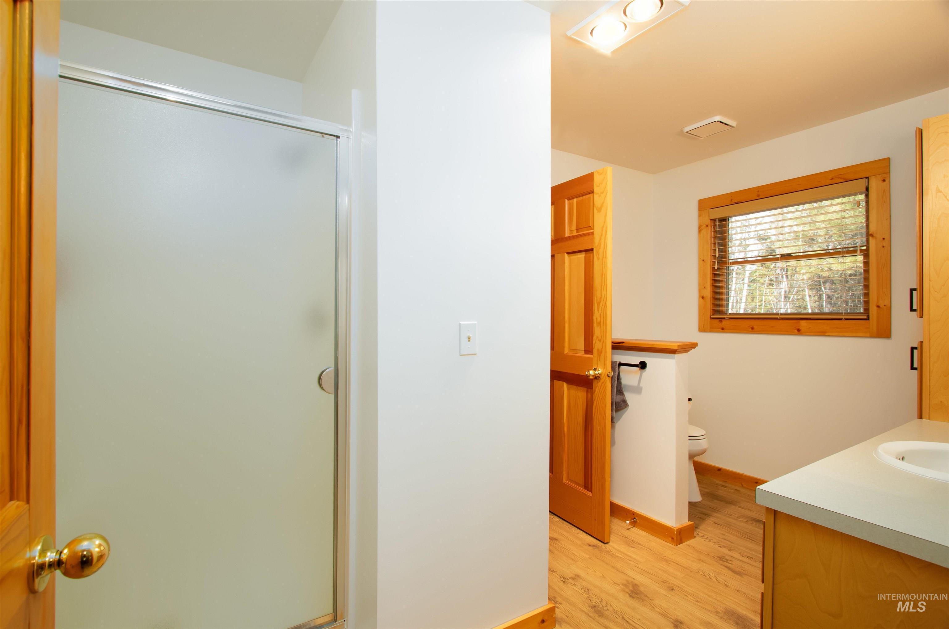 Full bathroom featuring vanity, a stall shower, and light wood-style floors