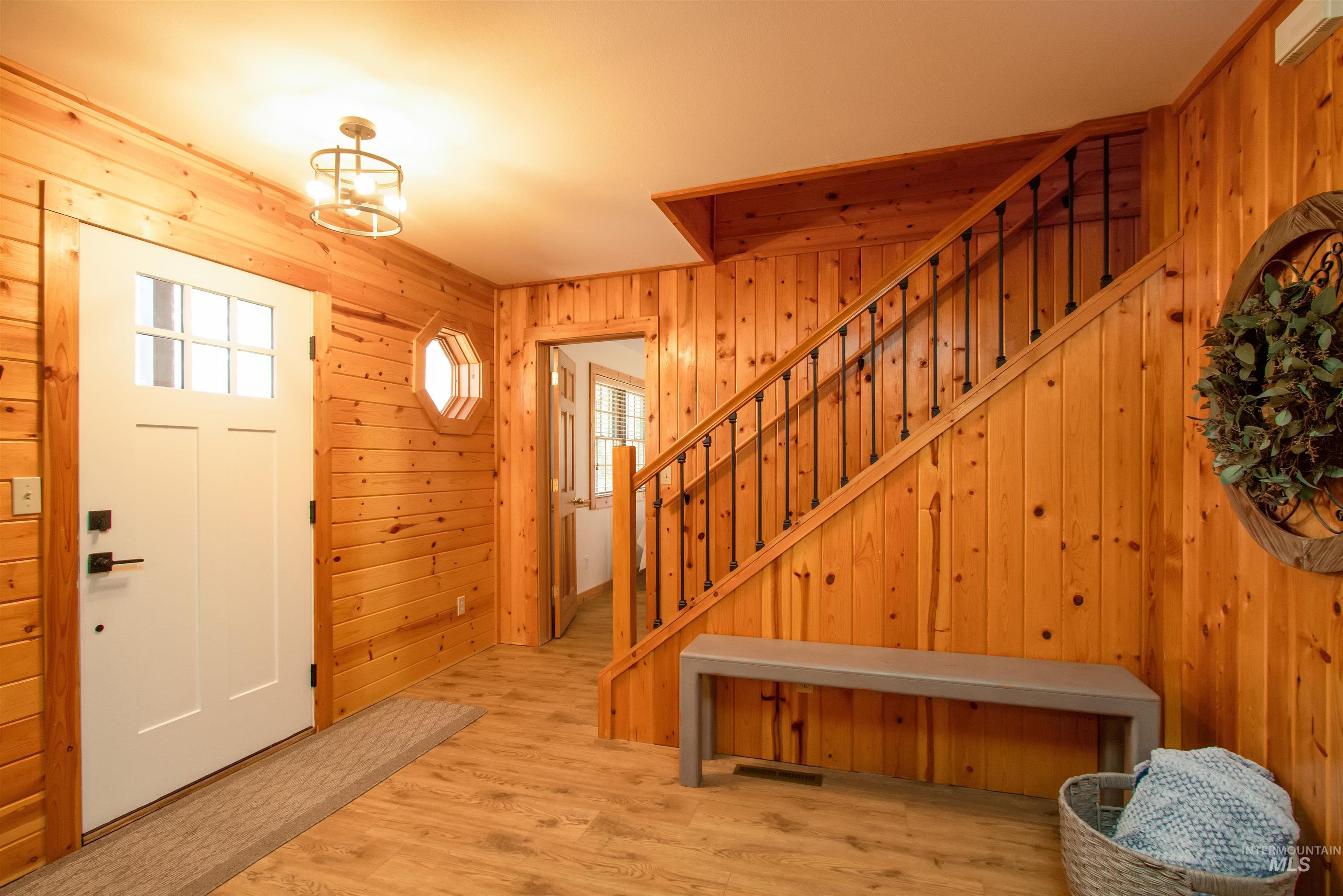 Foyer entrance with light wood-type flooring and wooden walls