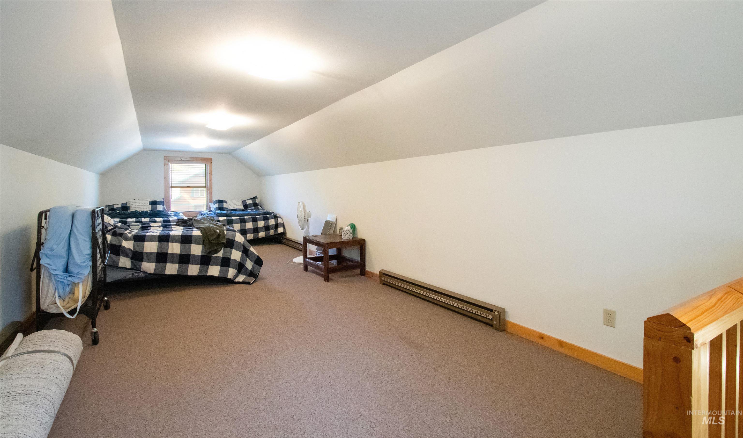 Carpeted bedroom with baseboards and a baseboard heating unit