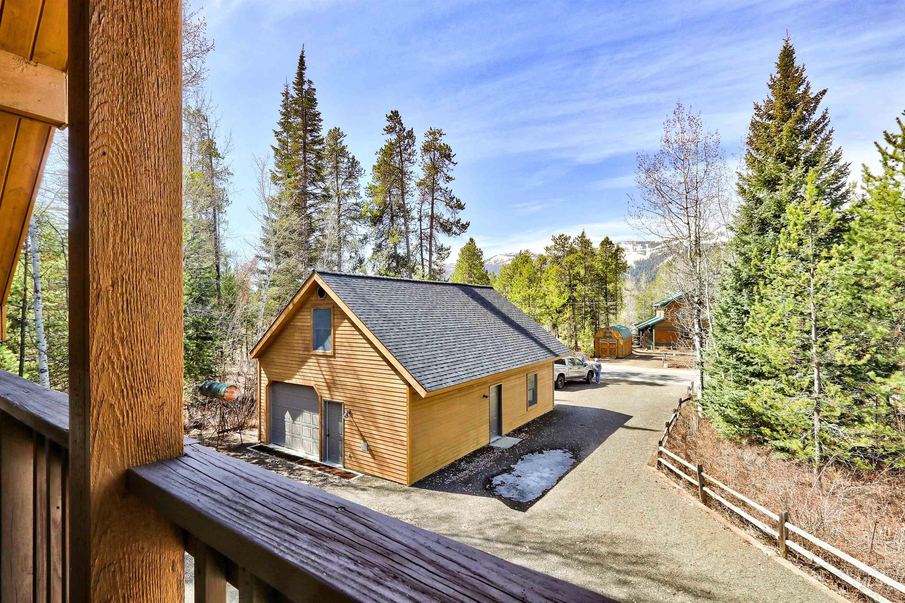 View of side of home with an outbuilding, roof with shingles, a detached garage, and a balcony