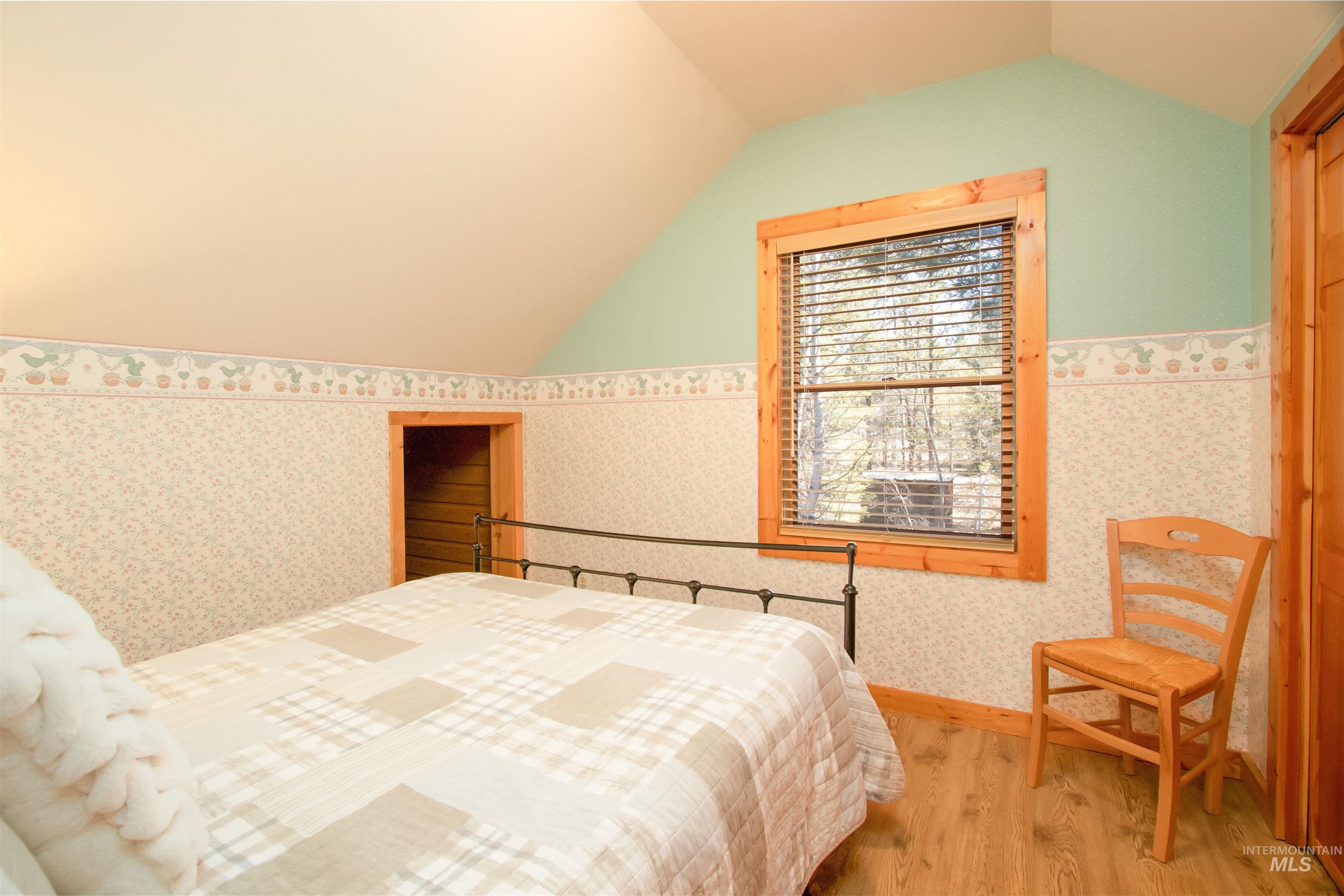Bedroom featuring wood finished floors and wallpapered walls