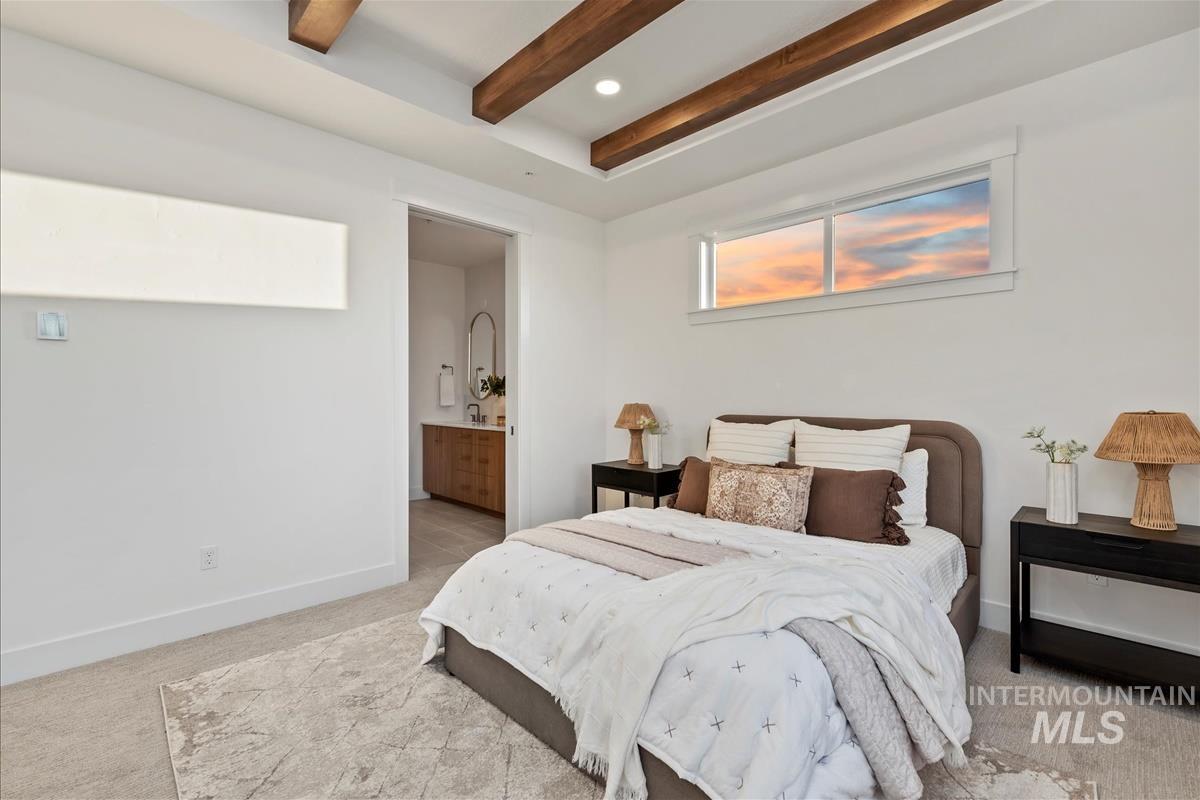 Bedroom with light carpet, beamed ceiling, and ensuite bath