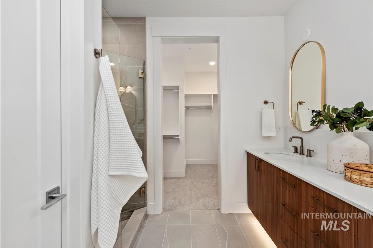Bathroom with vanity, light tile patterned floors, a spacious closet, and a shower stall