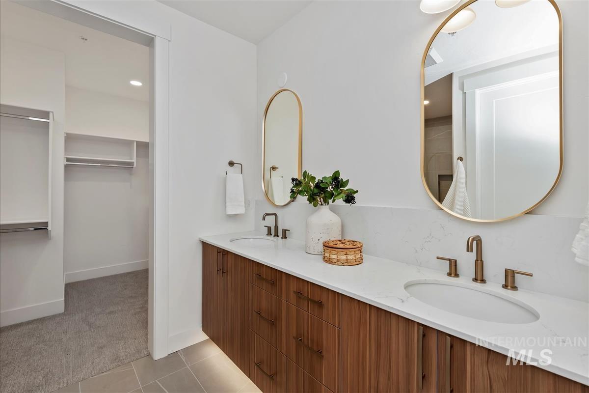 Bathroom with double vanity, light carpet, light tile patterned flooring, recessed lighting, and a walk in closet