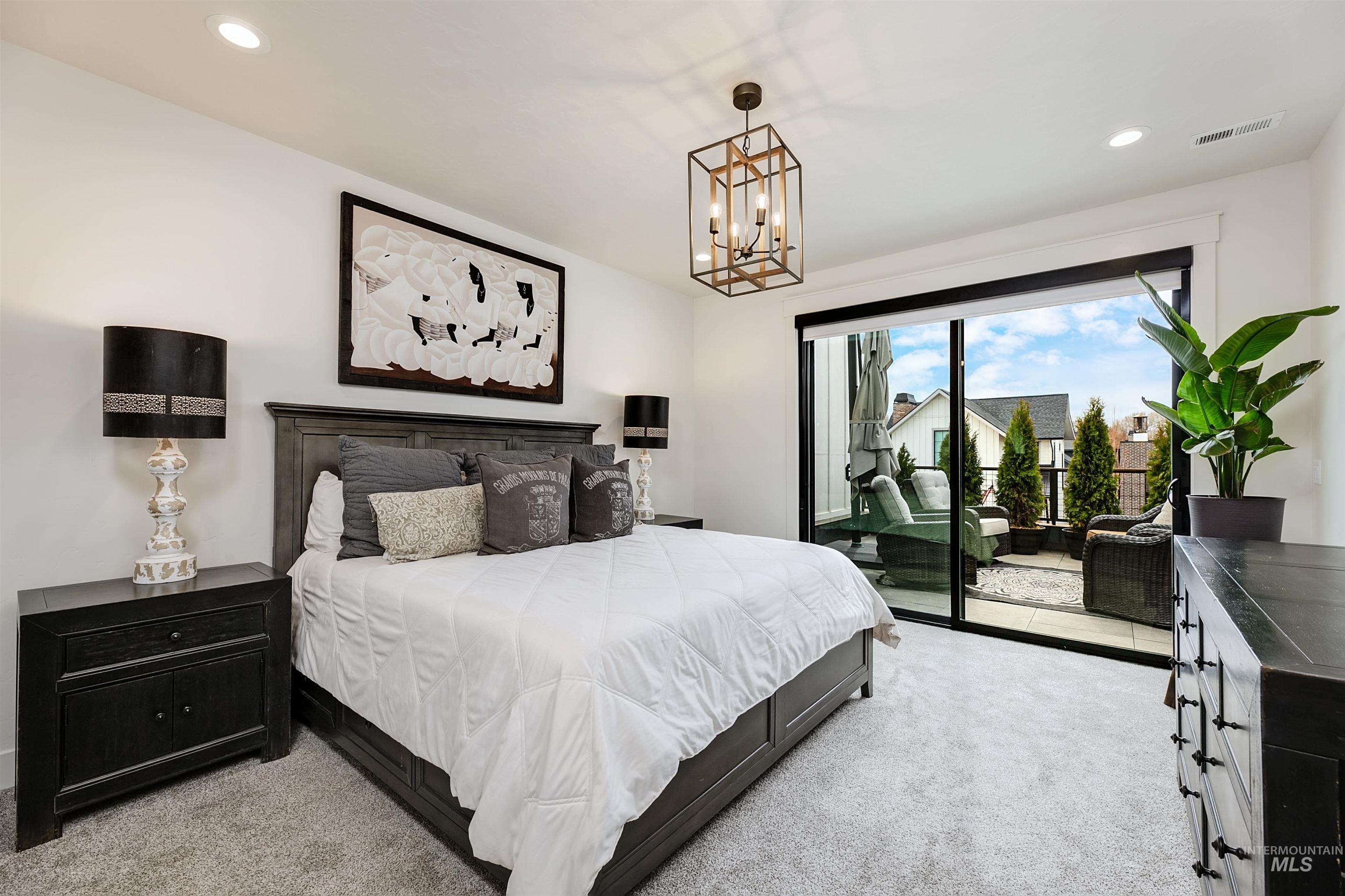 Bedroom with light colored carpet, access to exterior, and a chandelier