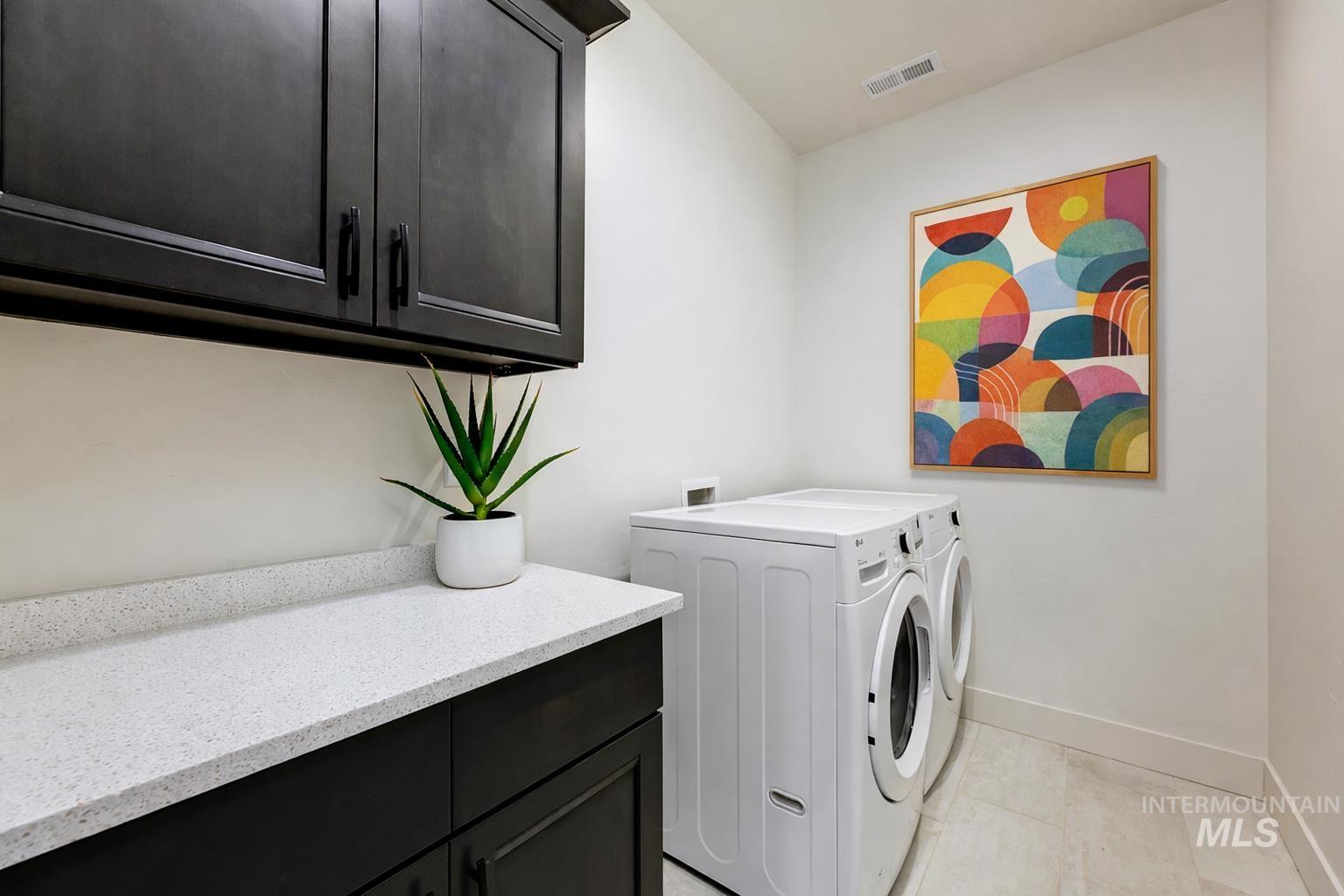 Laundry area featuring cabinet space, independent washer and dryer, and light tile patterned floors