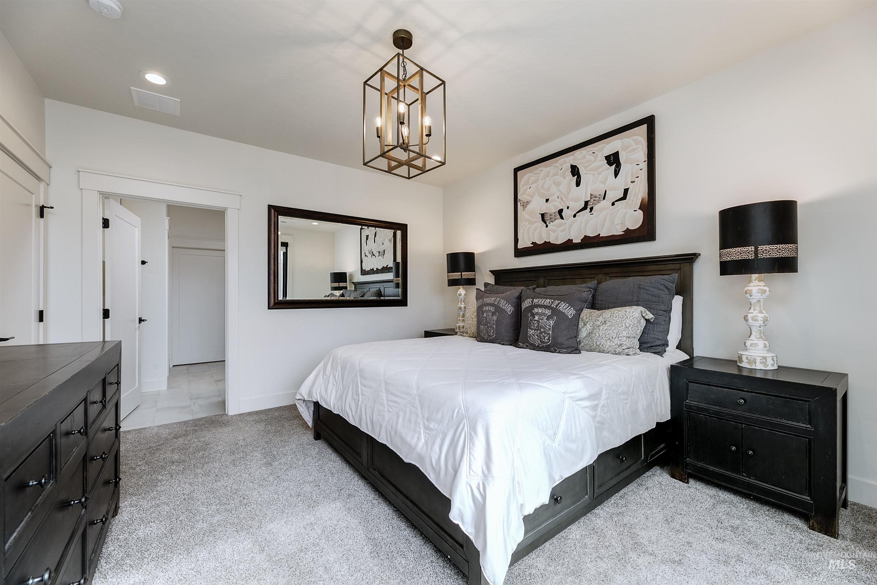 Bedroom with light colored carpet and hanging lights