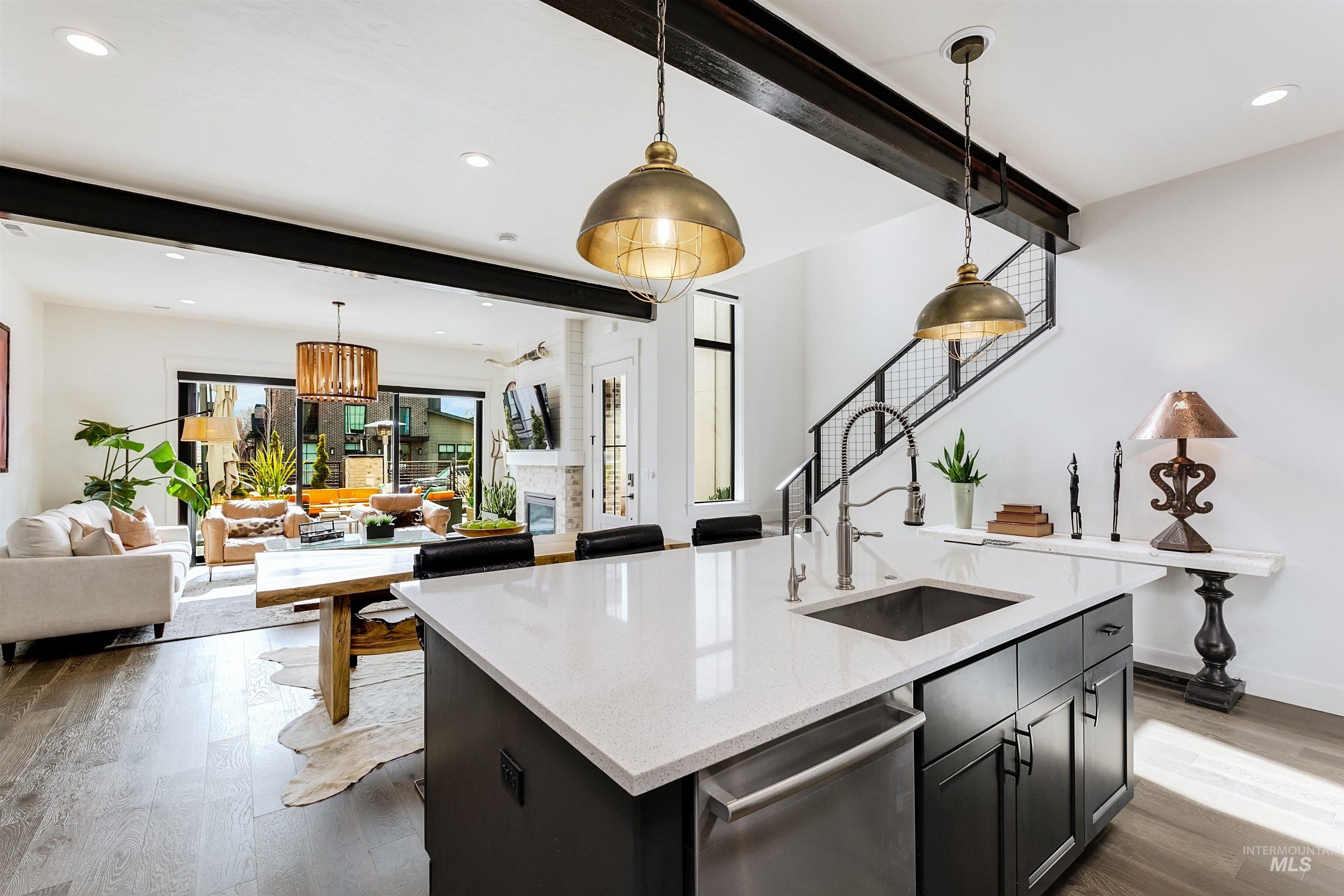 Kitchen with beamed ceiling, open floor plan, dark wood-style floors, dishwasher, and pendant lighting