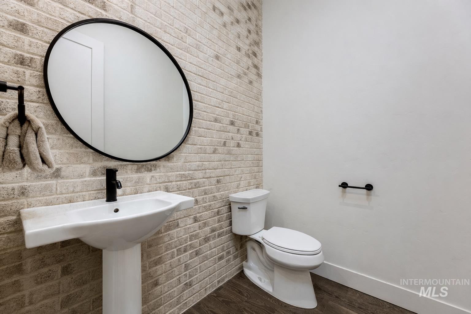 Bathroom with brick wall and dark wood-type flooring