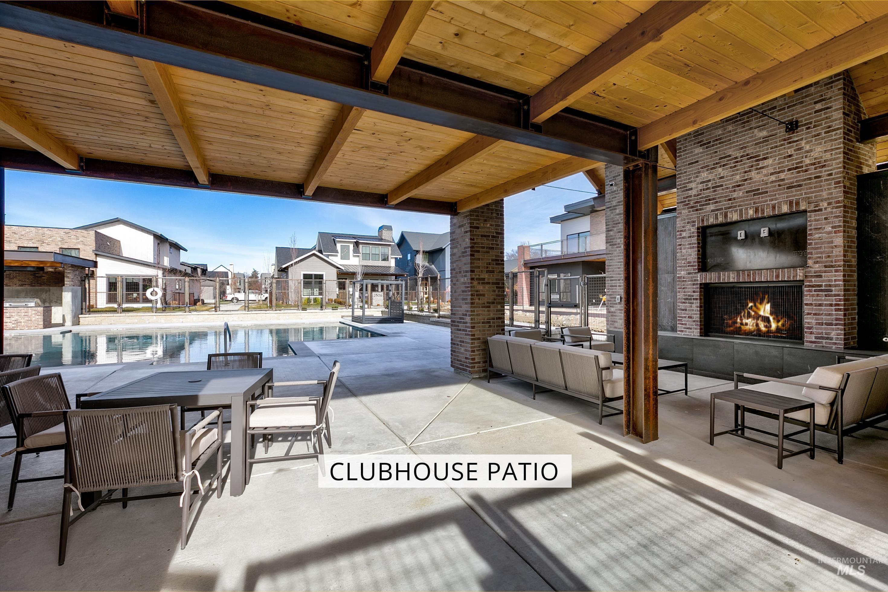 View of patio with an outdoor brick fireplace, a community pool, outdoor lounge area, and a residential view
