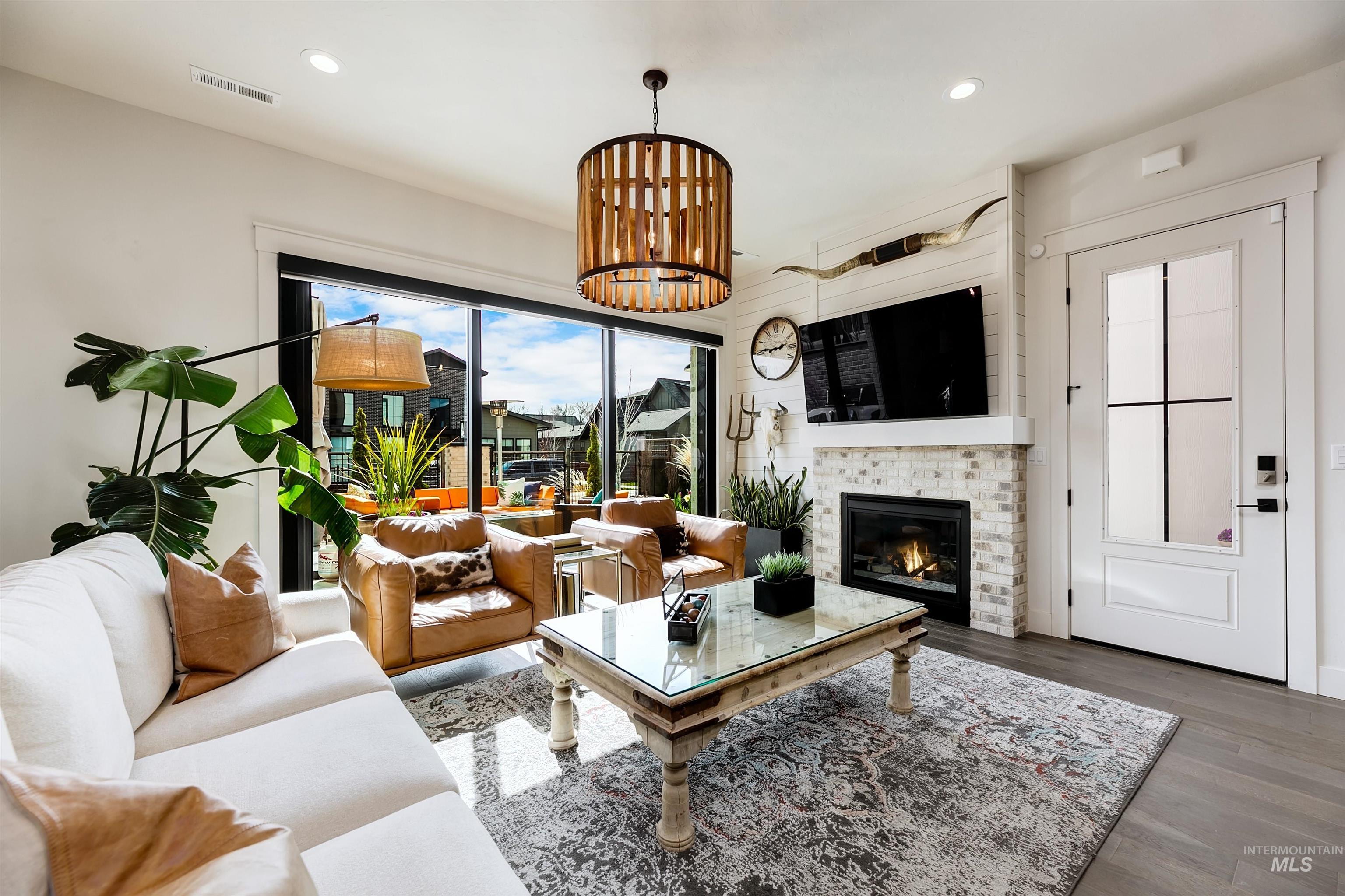 Living room with wood finished floors, a tiled fireplace, and a chandelier