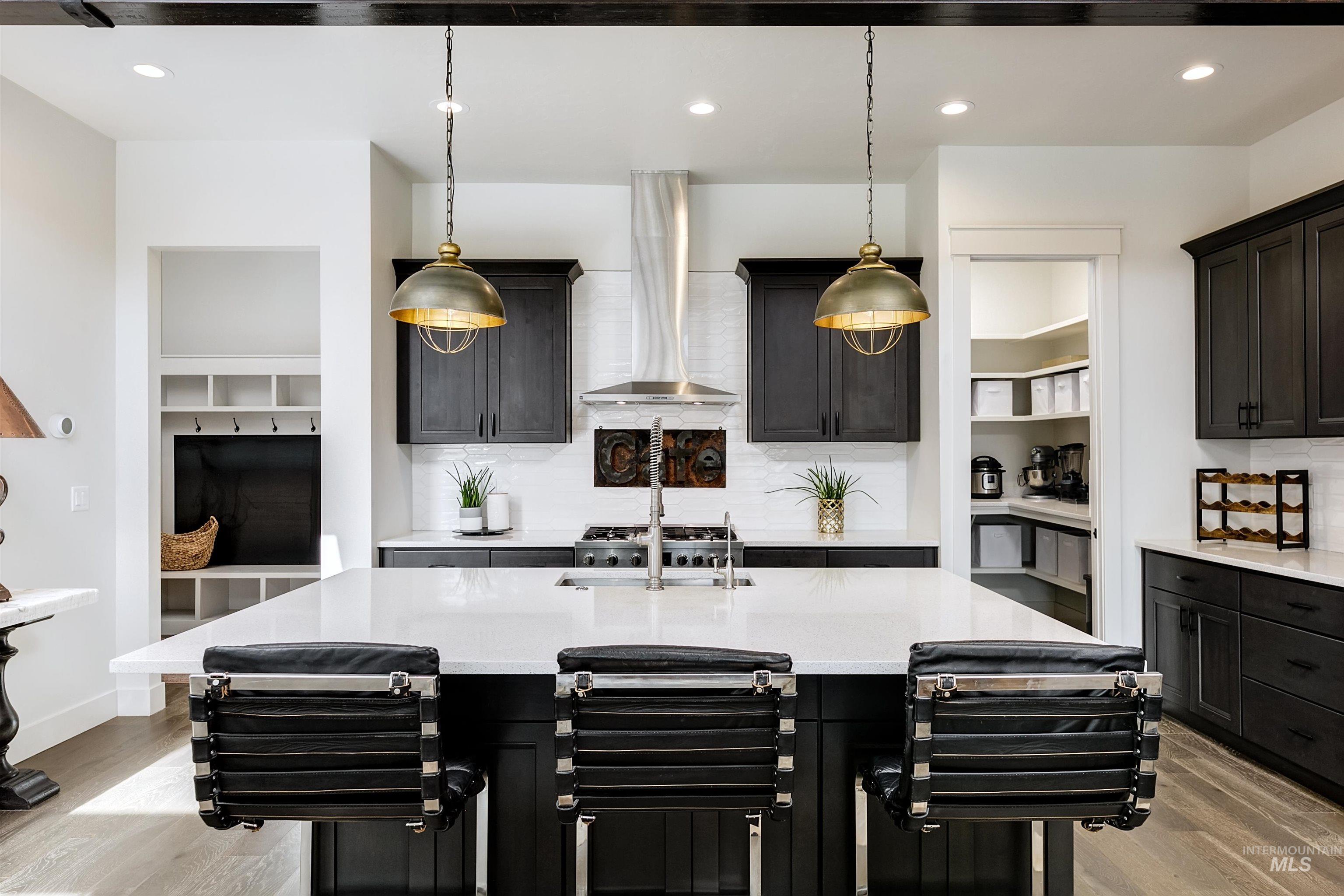 Kitchen with dark cabinets, light wood finished floors, light stone countertops, and tasteful backsplash