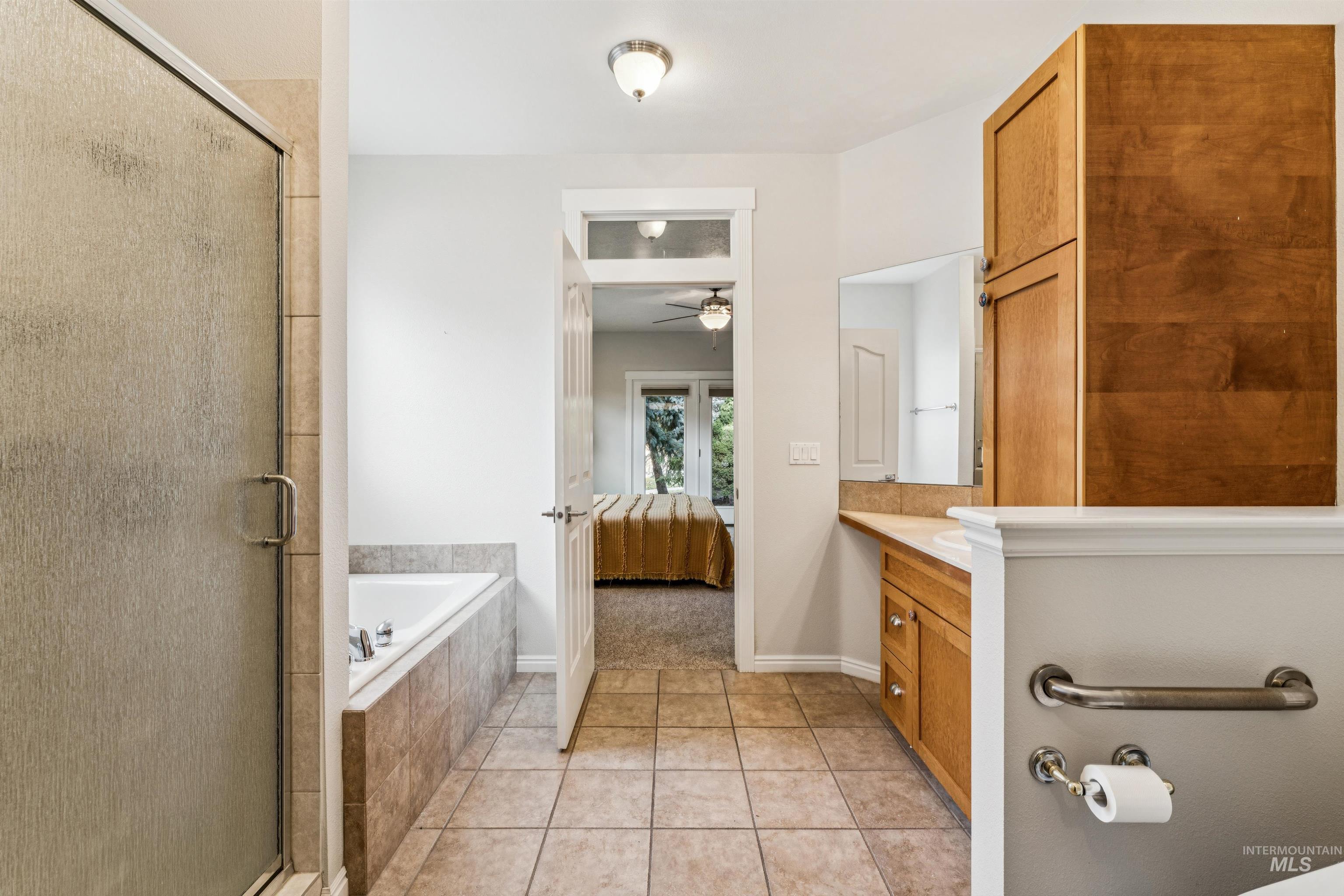 Full bathroom with ensuite bath, vanity, a stall shower, a bath, and light tile patterned floors