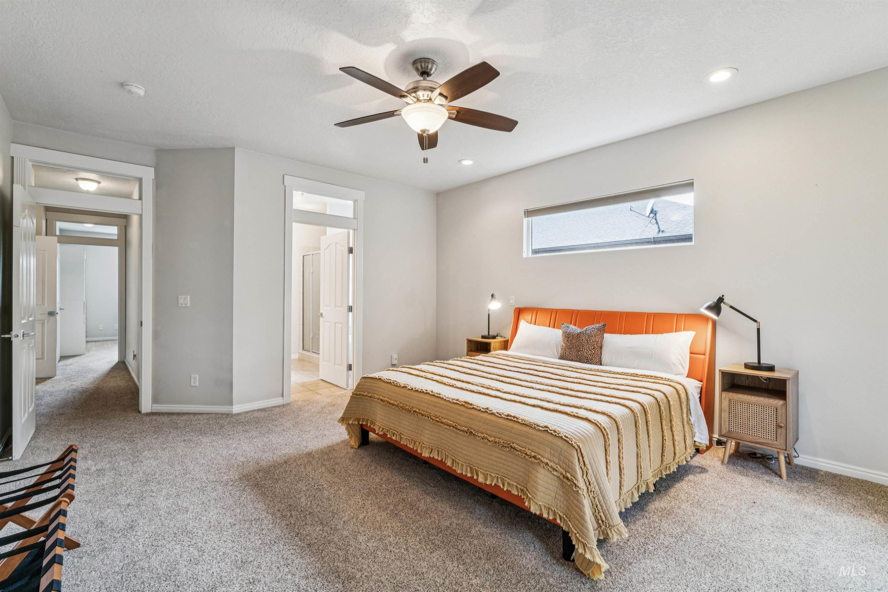 Bedroom with light colored carpet, ensuite bath, and a ceiling fan