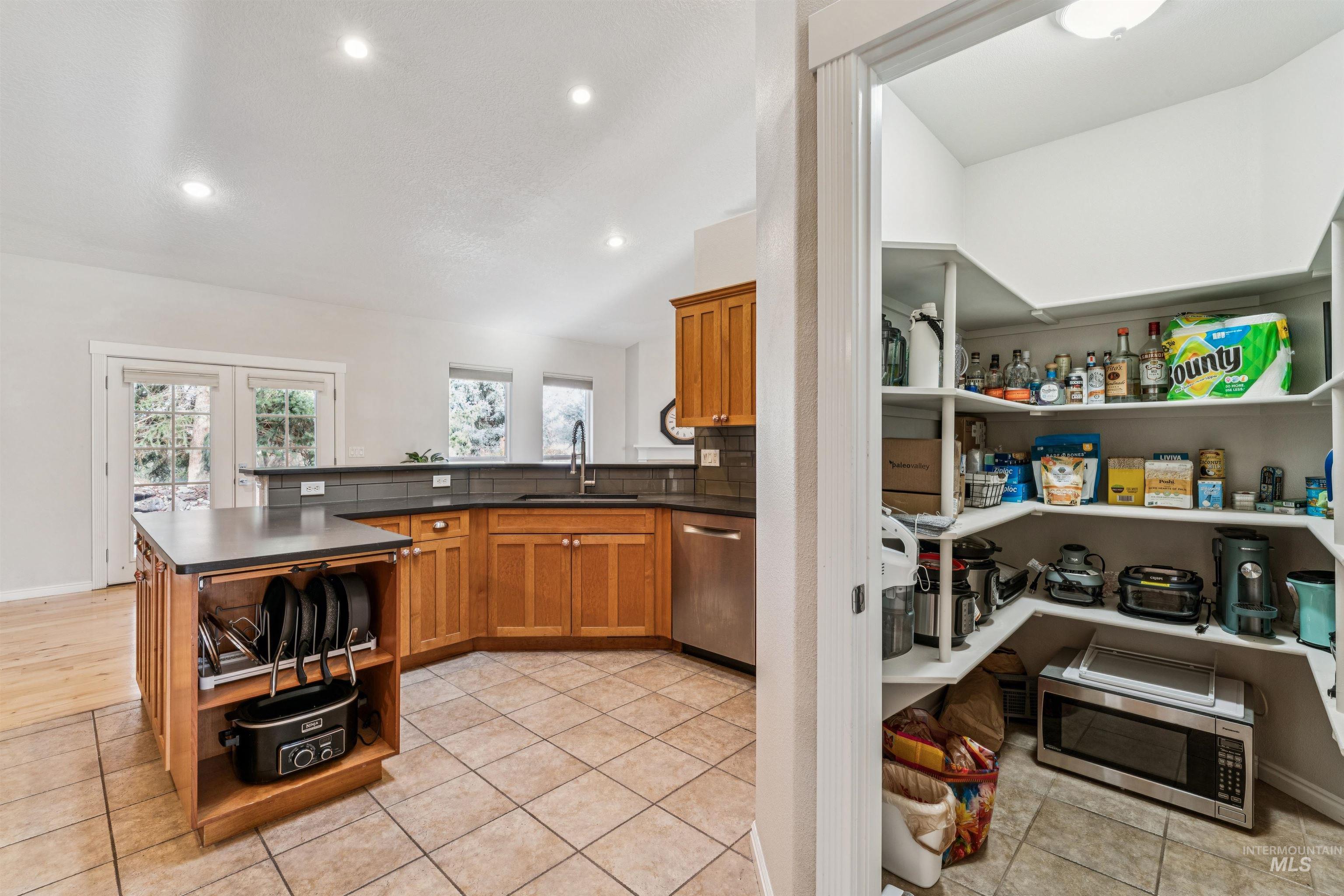 Kitchen featuring brown cabinetry, dark countertops, stainless steel appliances, a peninsula, and recessed lighting