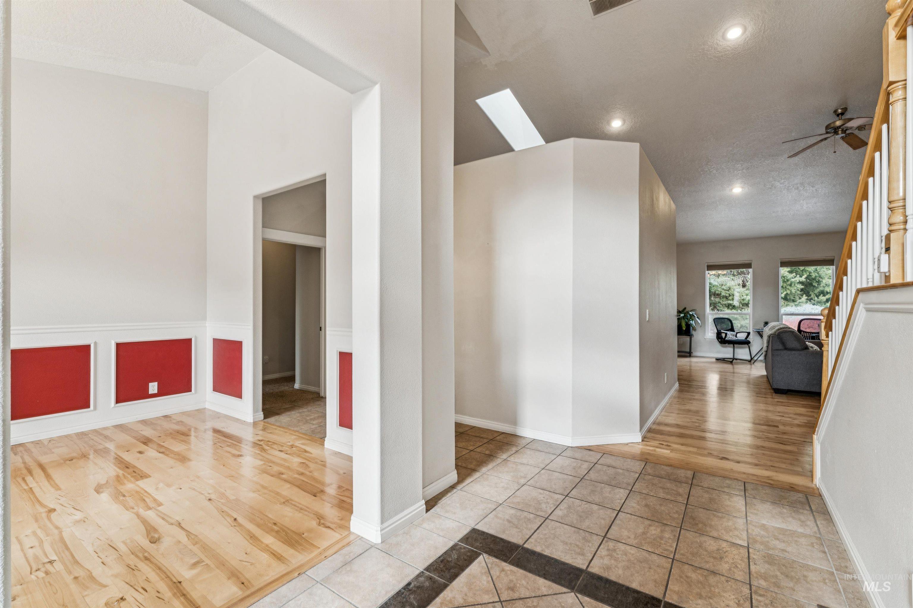 Hallway featuring light tile patterned floors, a textured ceiling, recessed lighting, a skylight, and stairway