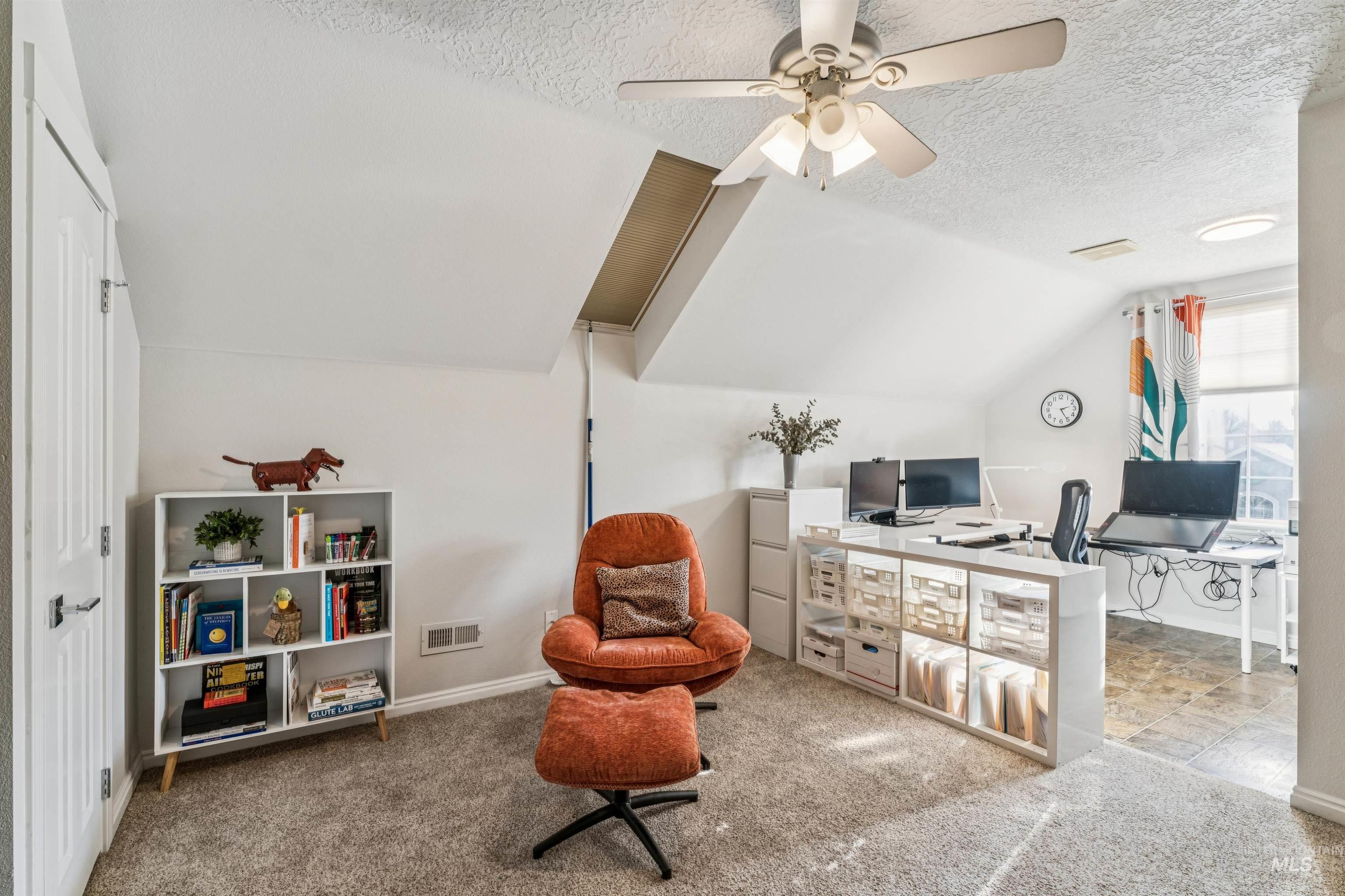 Office with vaulted ceiling, a textured ceiling, carpet flooring, and a ceiling fan