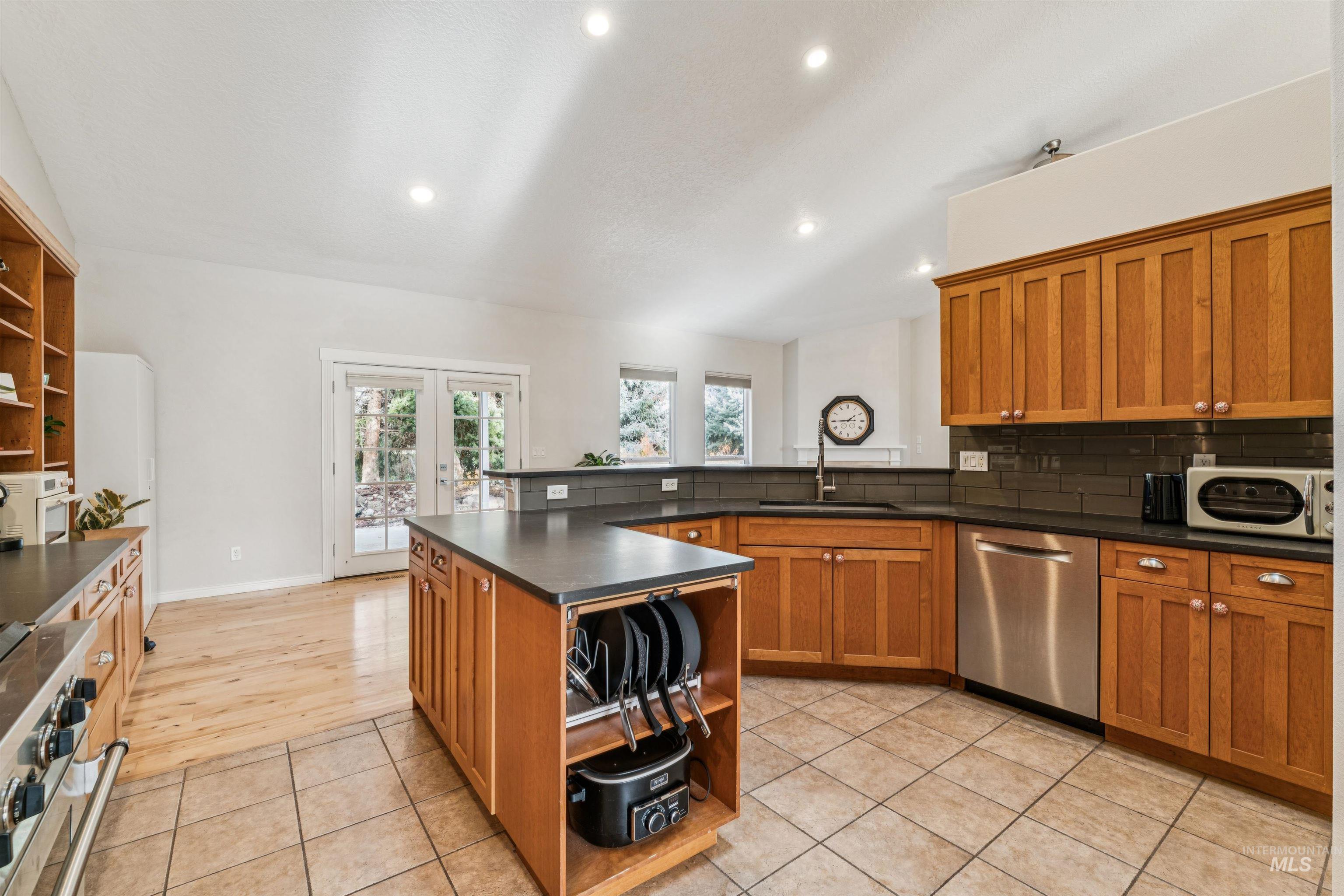 Kitchen featuring brown cabinetry, open shelves, dark countertops, and recessed lighting
