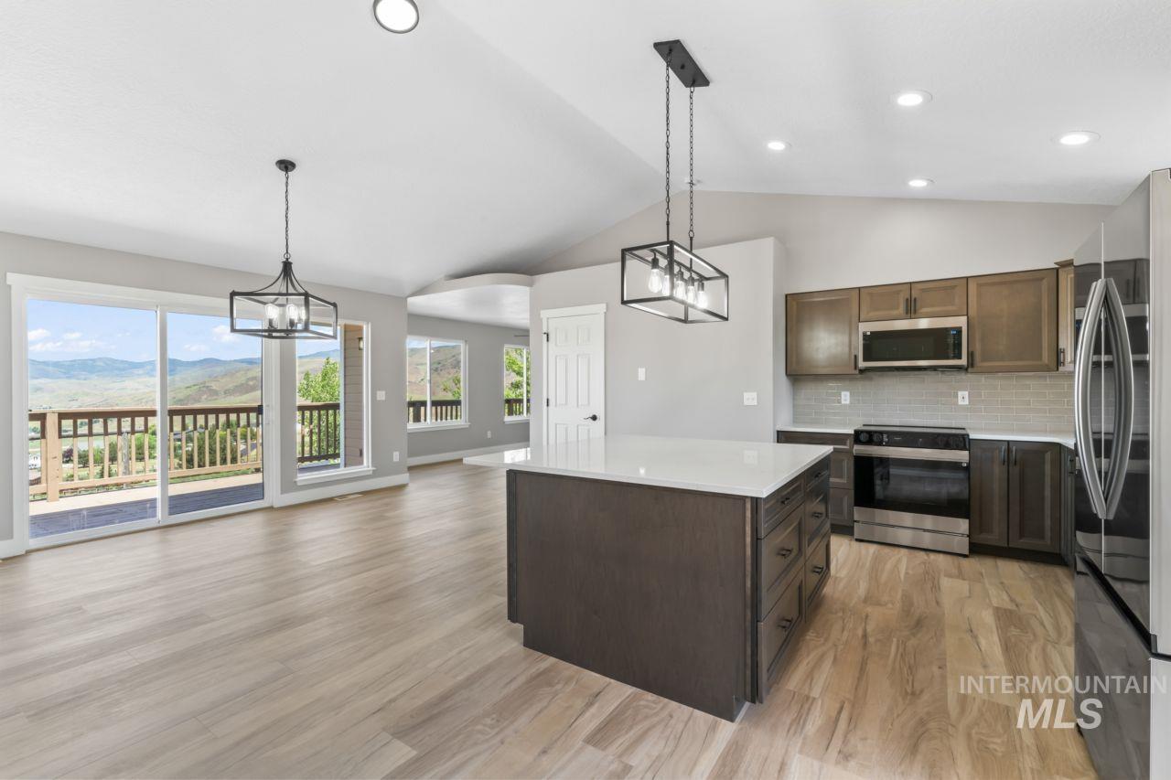 Kitchen with appliances with stainless steel finishes, light countertops, light wood-type flooring, tasteful backsplash, and a chandelier