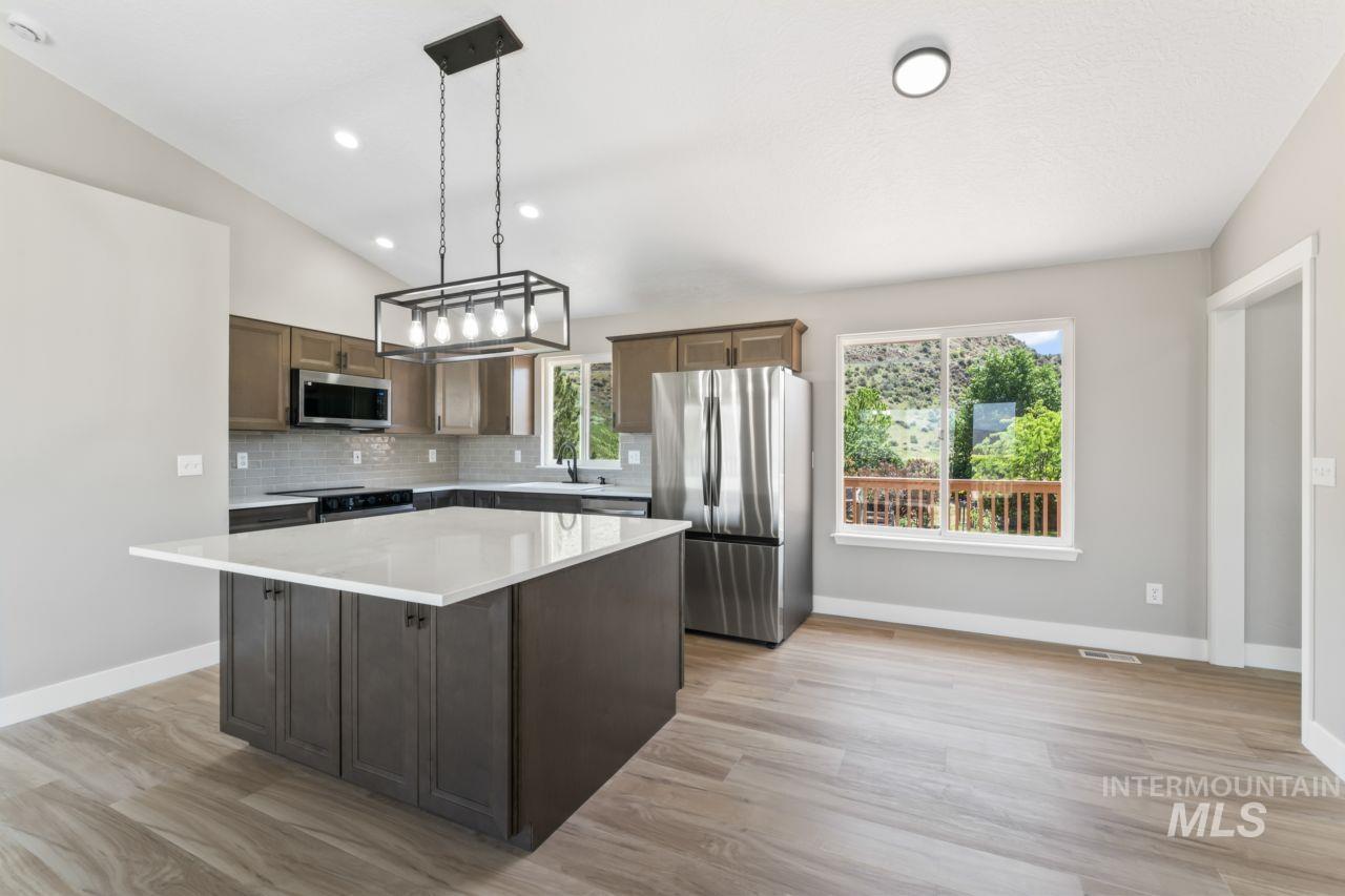 Kitchen featuring stainless steel appliances, a kitchen island, light countertops, tasteful backsplash, and plenty of natural light
