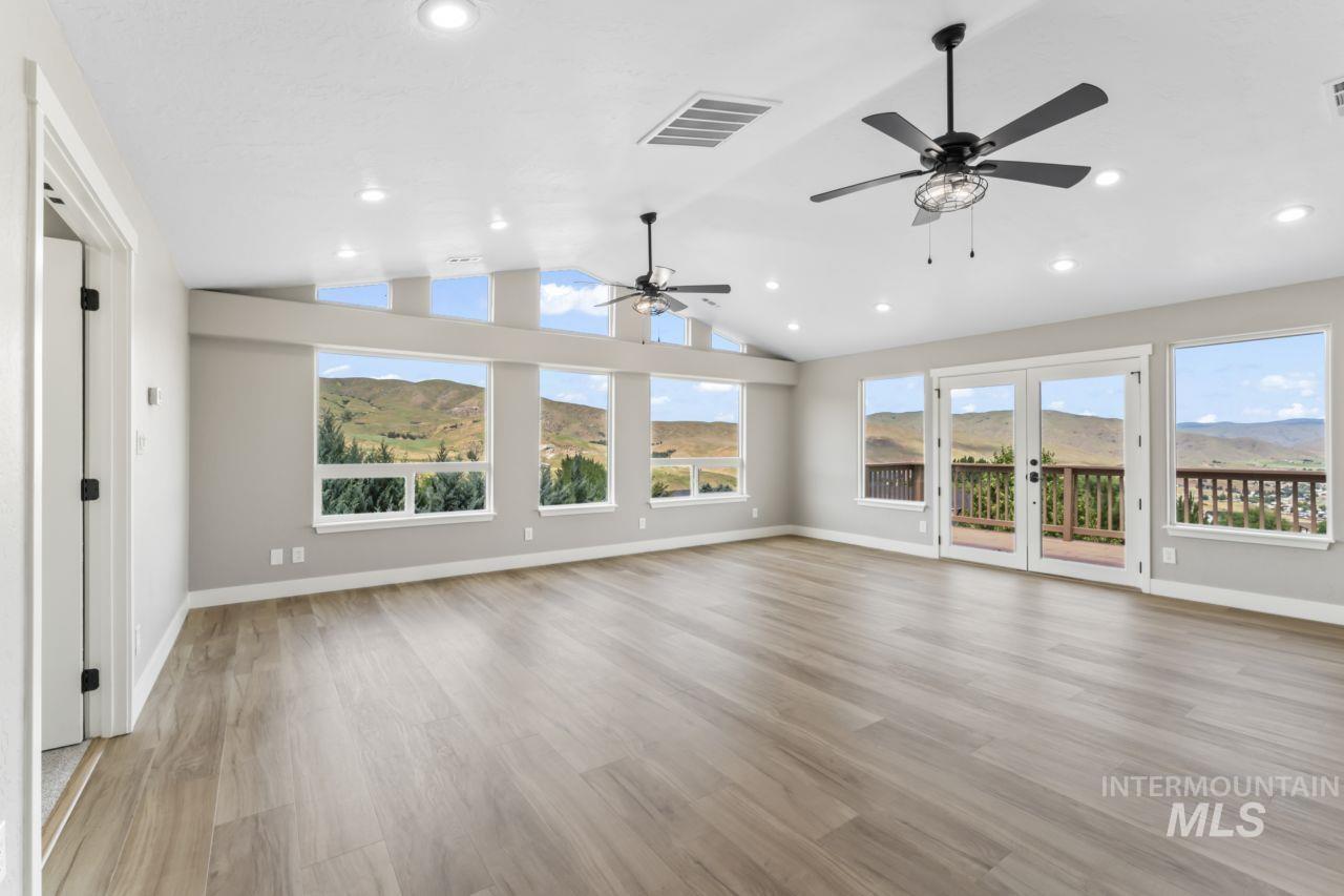 Unfurnished living room with ceiling fan, recessed lighting, lofted ceiling, french doors, and light wood-style floors