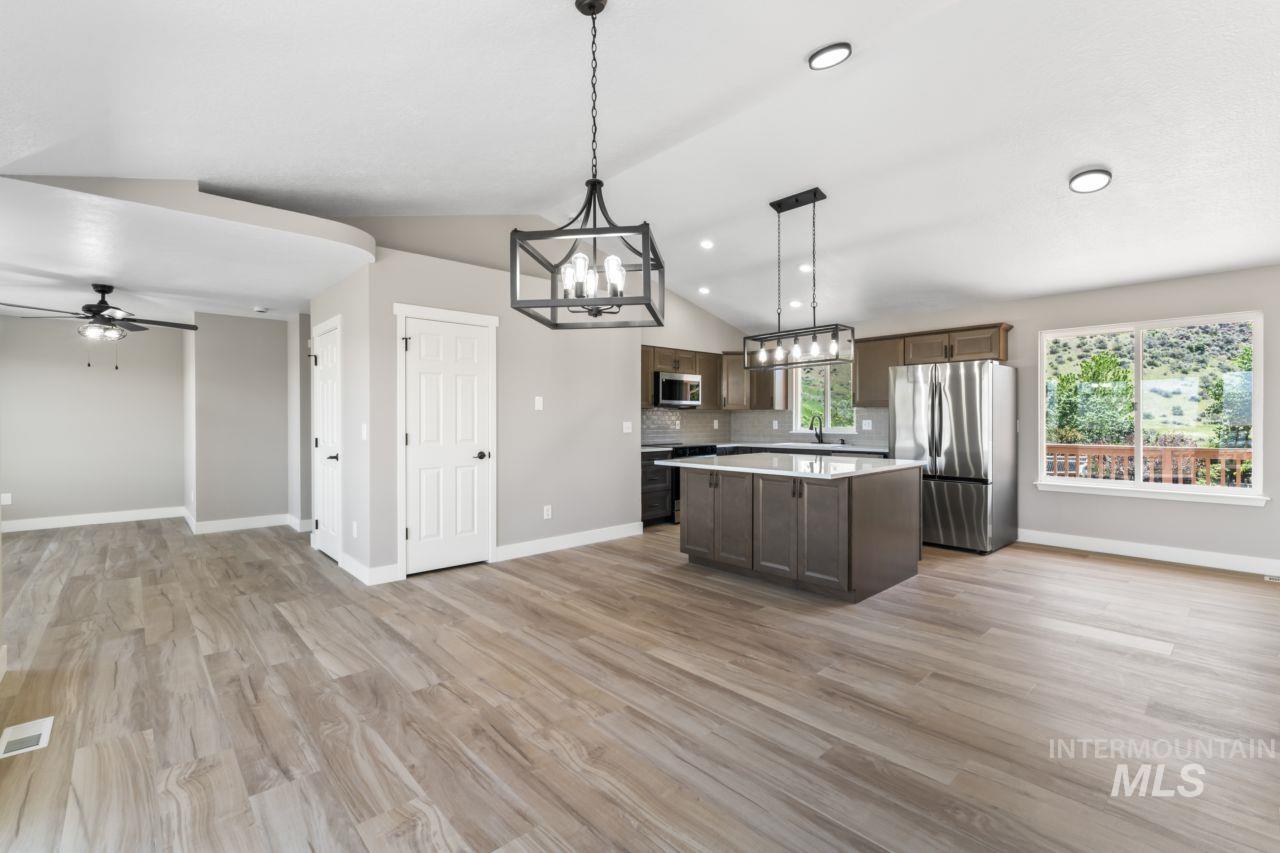 Kitchen with open floor plan, a chandelier, appliances with stainless steel finishes, a kitchen island, and light countertops