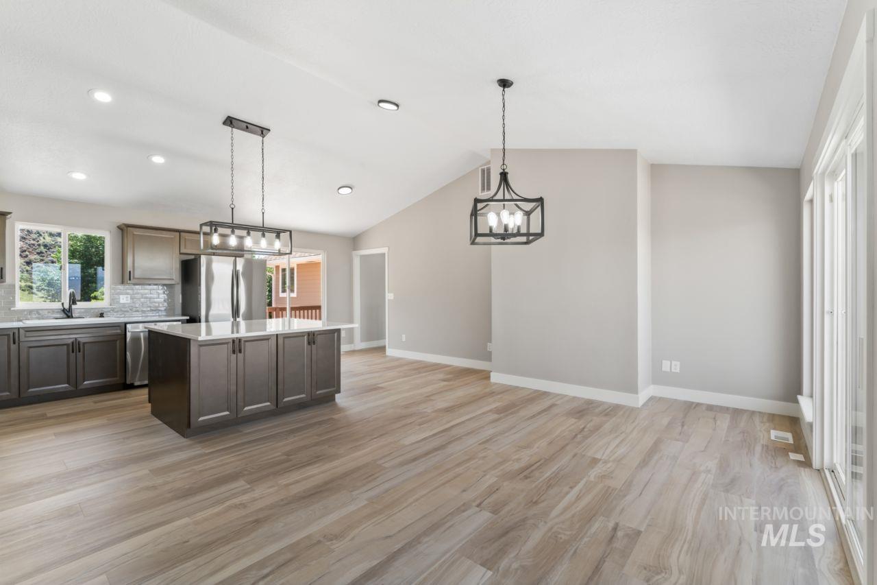 Kitchen with a chandelier, a center island, light countertops, stainless steel appliances, and light wood-type flooring