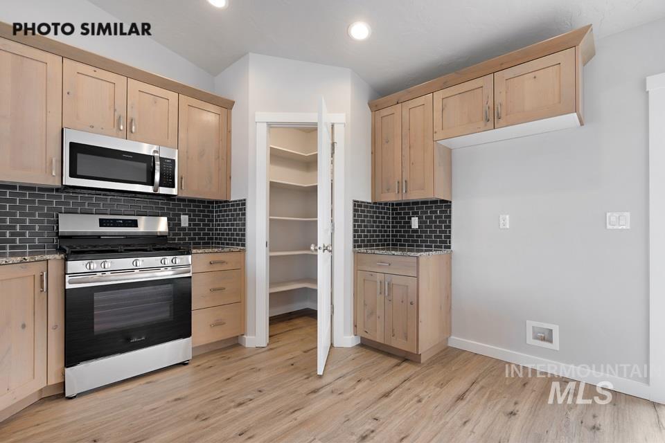 Kitchen with light brown cabinets, appliances with stainless steel finishes, light wood-style flooring, and recessed lighting