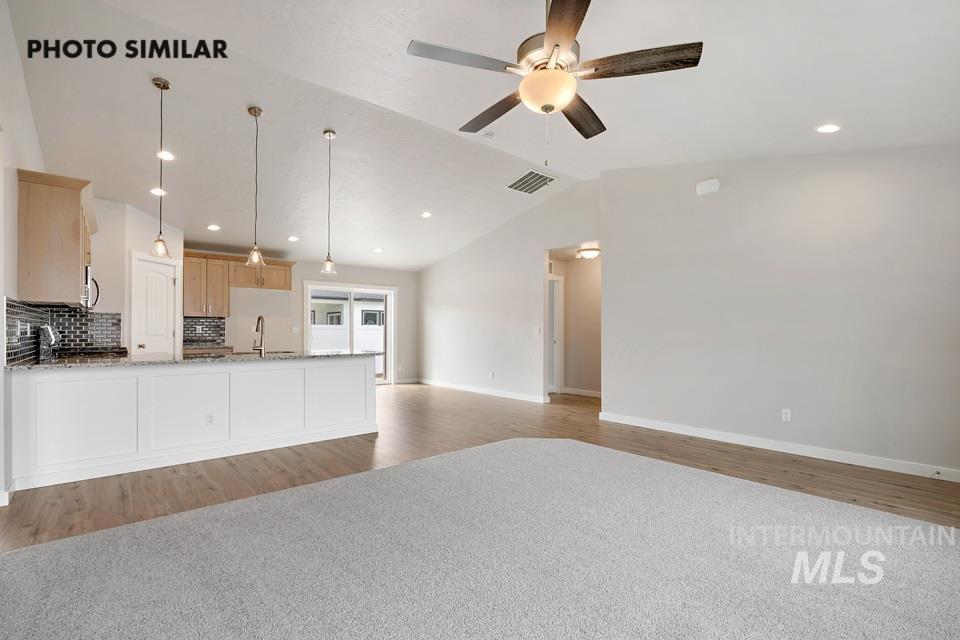 Kitchen featuring vaulted ceiling, recessed lighting, a ceiling fan, open floor plan, and light wood-type flooring