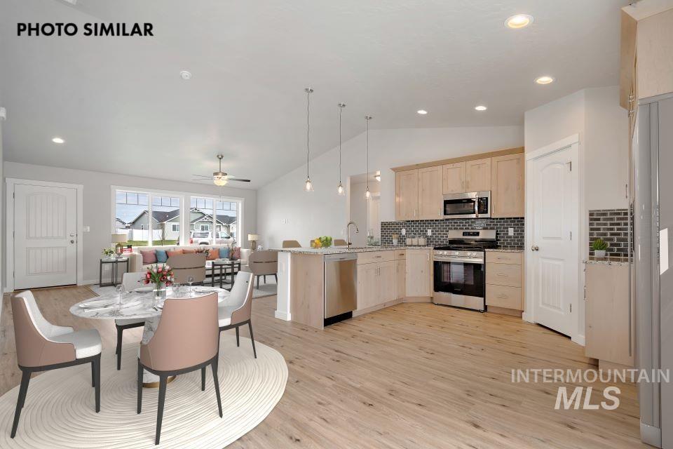 Kitchen with light brown cabinets, a peninsula, vaulted ceiling, tasteful backsplash, and stainless steel appliances