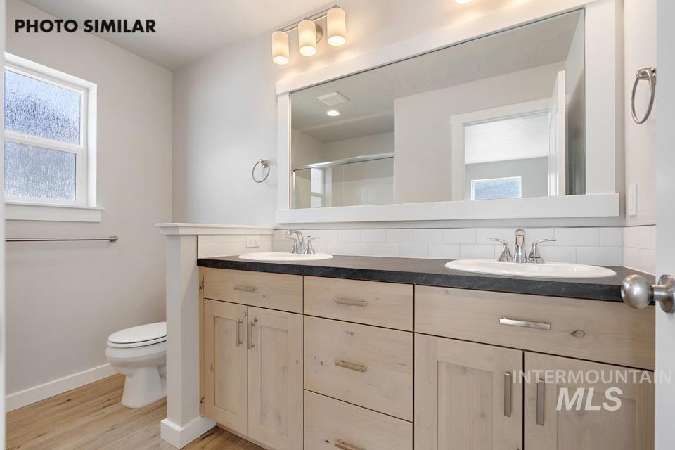 Bathroom with tasteful backsplash, double vanity, a shower with door, and wood finished floors