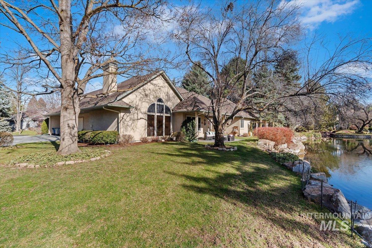 View of front of property with stucco siding, a front lawn, a chimney, and a water view