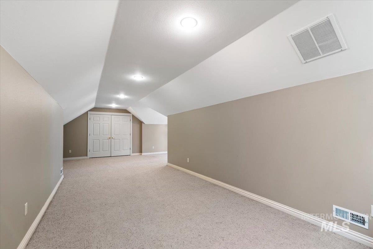 Bonus room featuring baseboards and light carpet