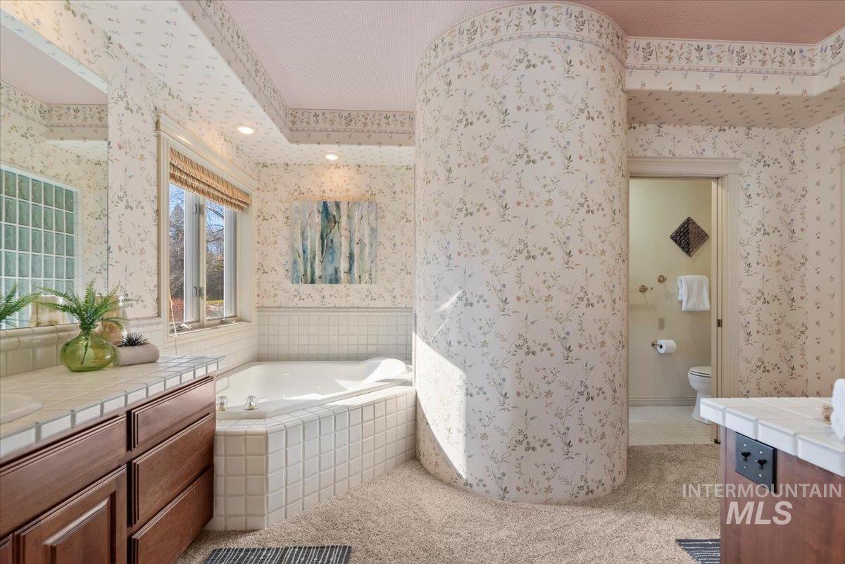 Full bathroom with vanity, a garden tub, light carpet, and wallpapered walls