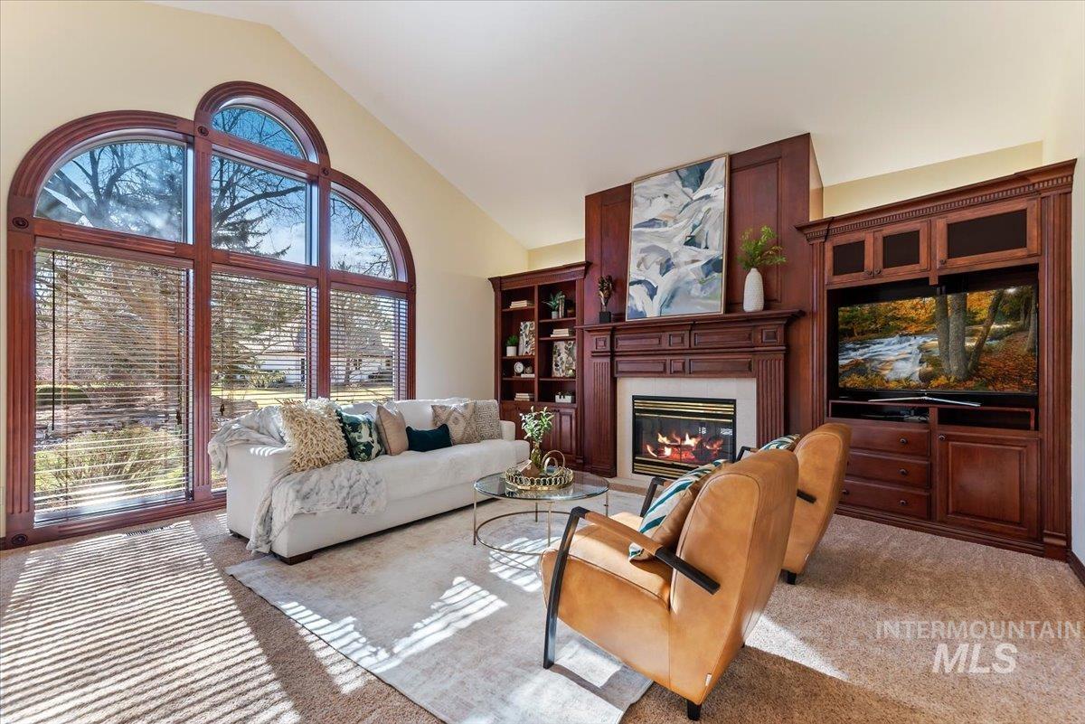 Carpeted living area featuring a glass covered fireplace and lofted ceiling