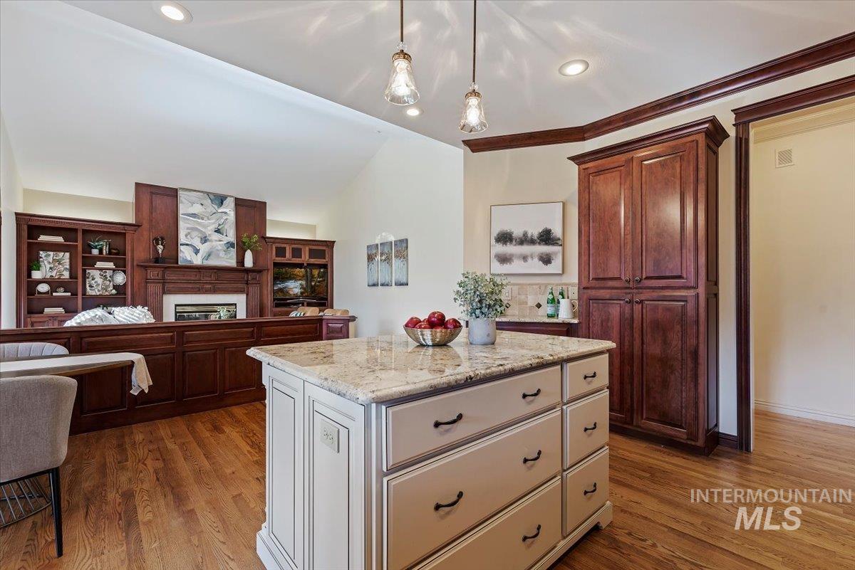Kitchen featuring two tone color scheme, light stone countertops, a large fireplace, open floor plan, and dark wood finished floors