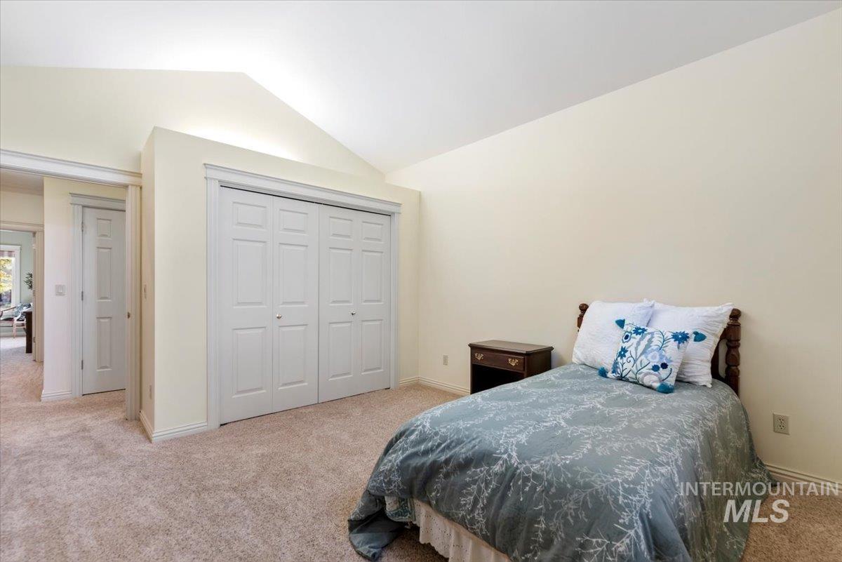 Bedroom with light carpet, lofted ceiling, and a closet