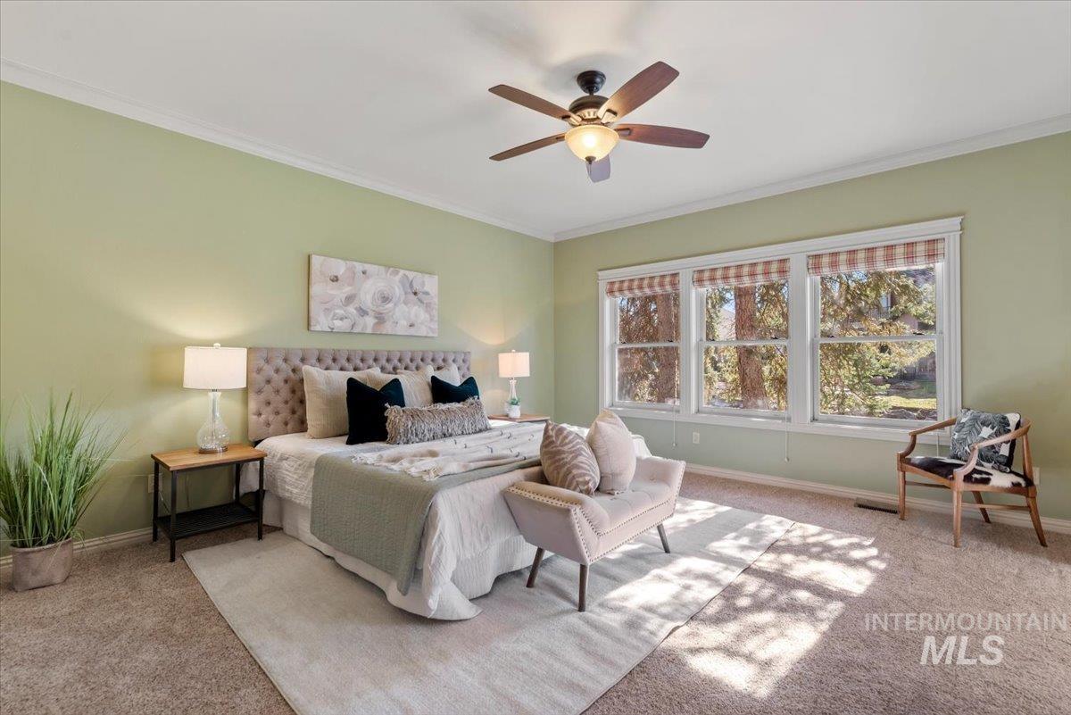 Bedroom featuring carpet, ornamental molding, and a ceiling fan