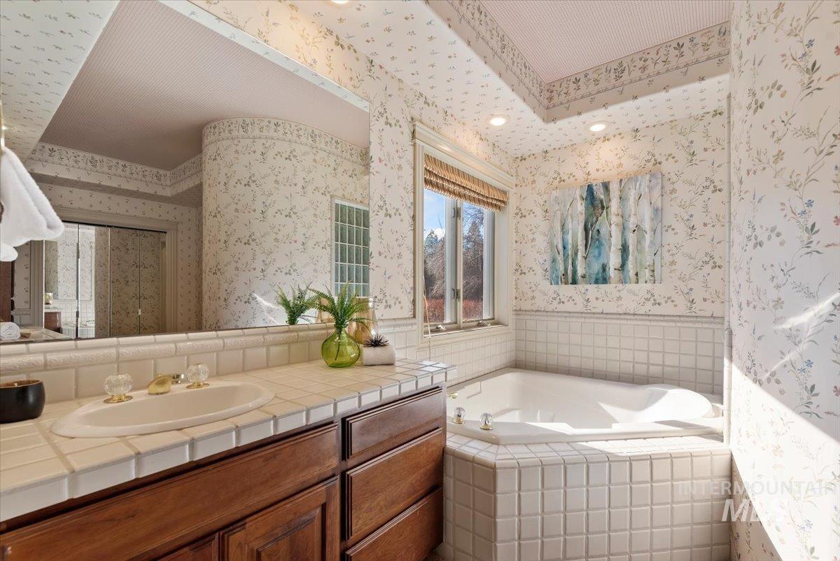 Bathroom featuring vanity, a garden tub, and wallpapered walls